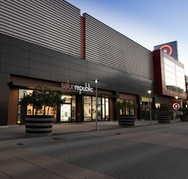 Exterior view of a Target store with a Salon Republic salon entrance in front, during the evening. Large planters with trees are outside, and the sky is clear. Med Spa in Hermosa Beach, CA | Nua Aesthetics
