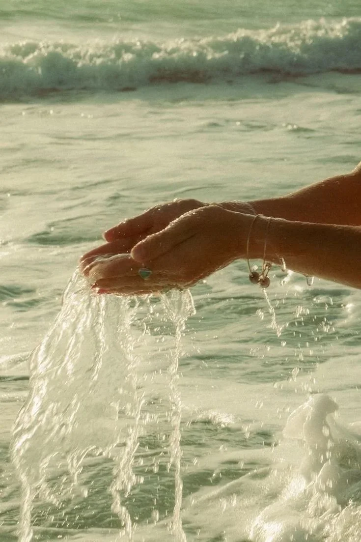 Person holding water from the ocean with their hands.