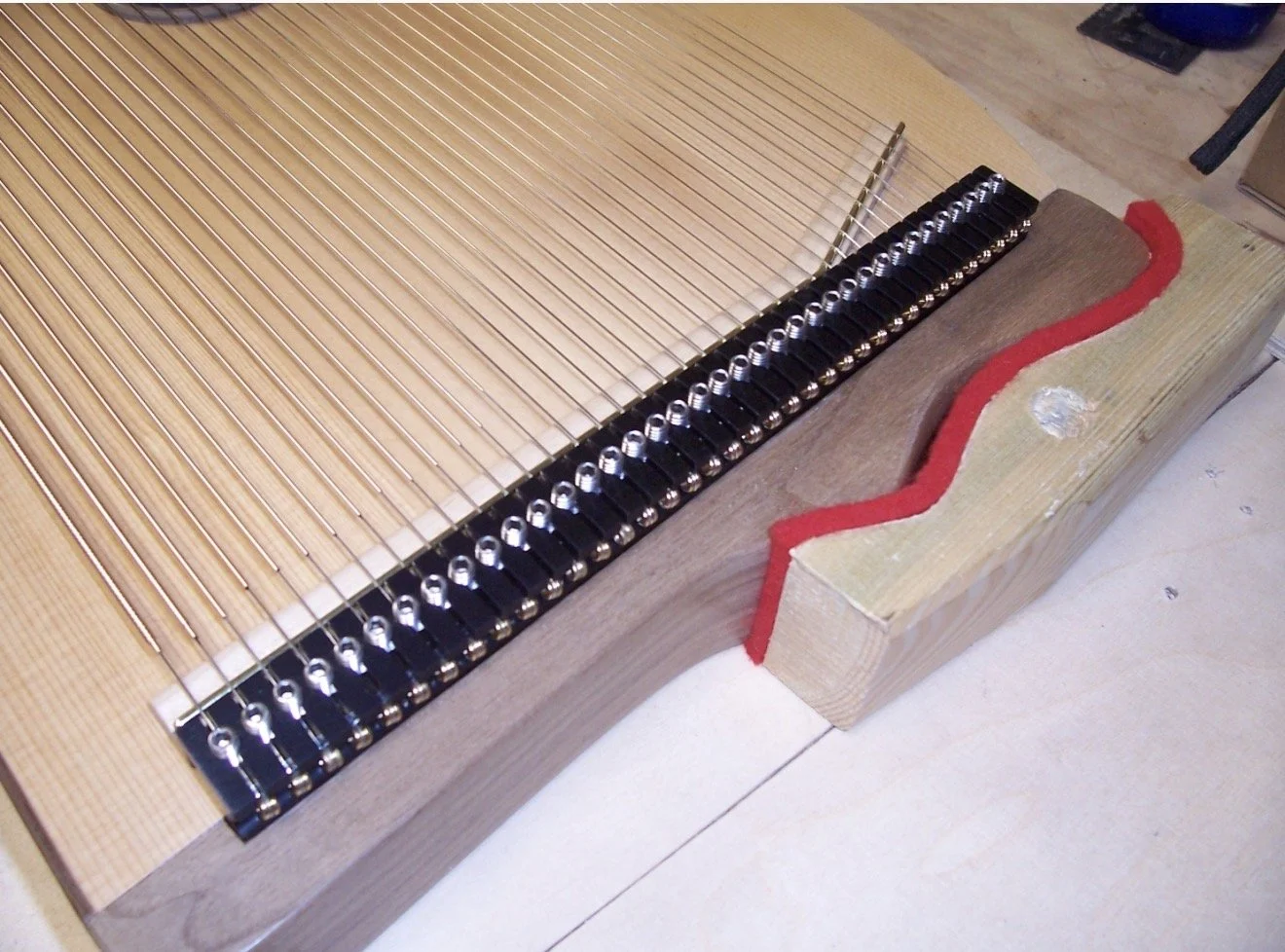 Images of harp after undergoing the polishing process, making and gluing on the bridges, installing the bridge pins, polished bridge caps and stringing up