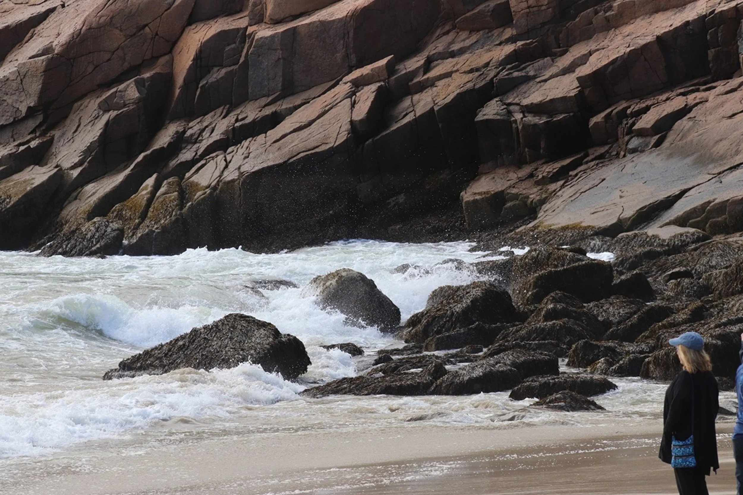 Watching the Atlantic - Rugged Maine Coast: Visitors stand quietly along the shoreline as waves break against weathered granite ledges, capturing the timeless attraction of Maine's rugged coast. The image combines human scale with dramatic natural sc