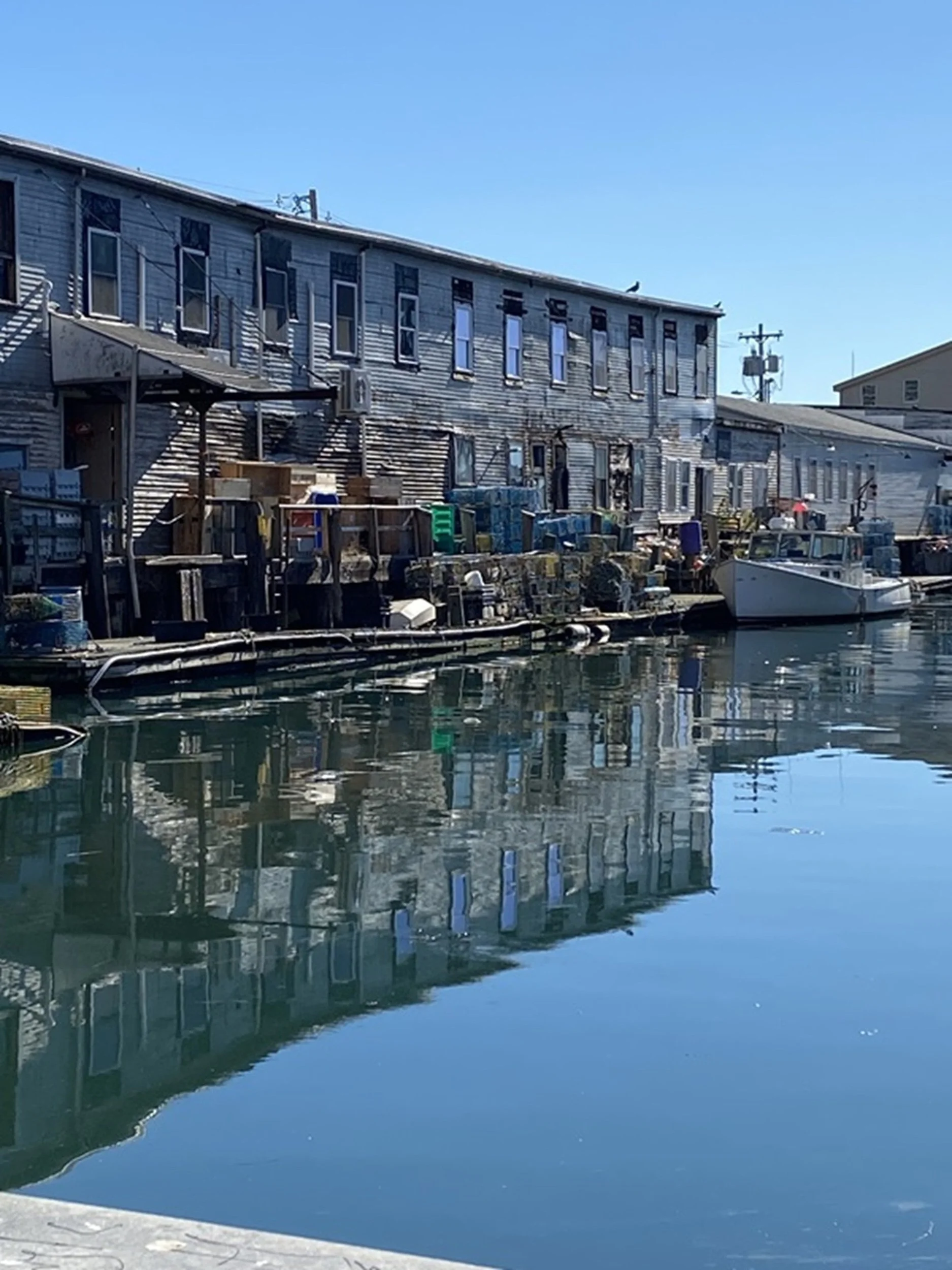 Historic Wharf Buildings on Portland's Working Waterfront: Weathered wharf buildings line a quiet harbor channel, reflecting generations of maritime industry and coastal resilience. The layered textures and authentic waterfront character make this im