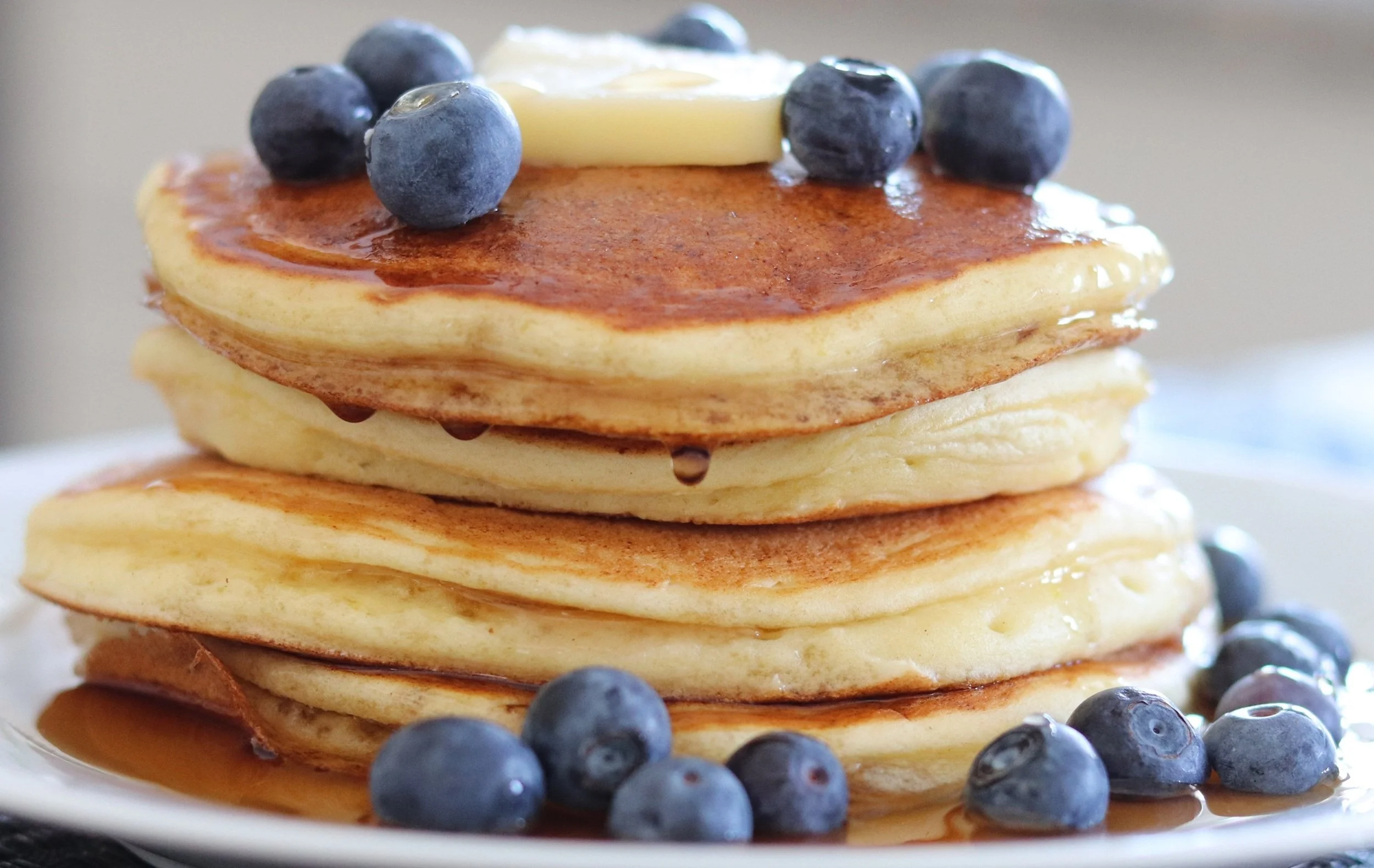 Morning Stack: A stack of golden pancakes topped with fresh blueberries and maple syrup evokes the timeless appeal of a leisurely breakfast. Rich in texture, color, and comfort, this image is perfectly suited for hotel dining venues, breakfast lounge