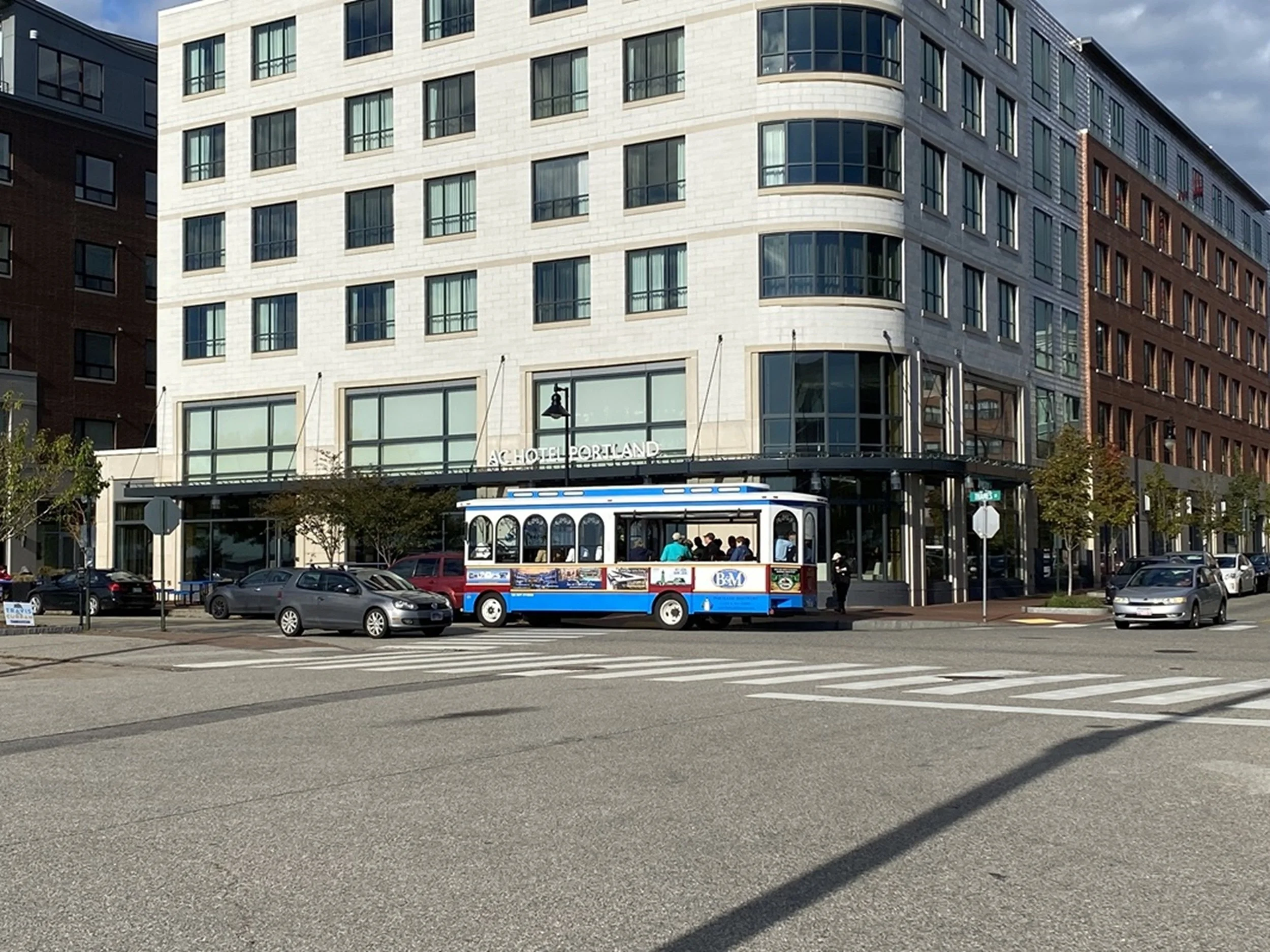 City Arrival - Portland Street Scene: A vintage trolley passes beneath the clean lines of Portland’s modern waterfront architecture, capturing the intersection of heritage, movement, and contemporary urban life. This image brings energy and regional 