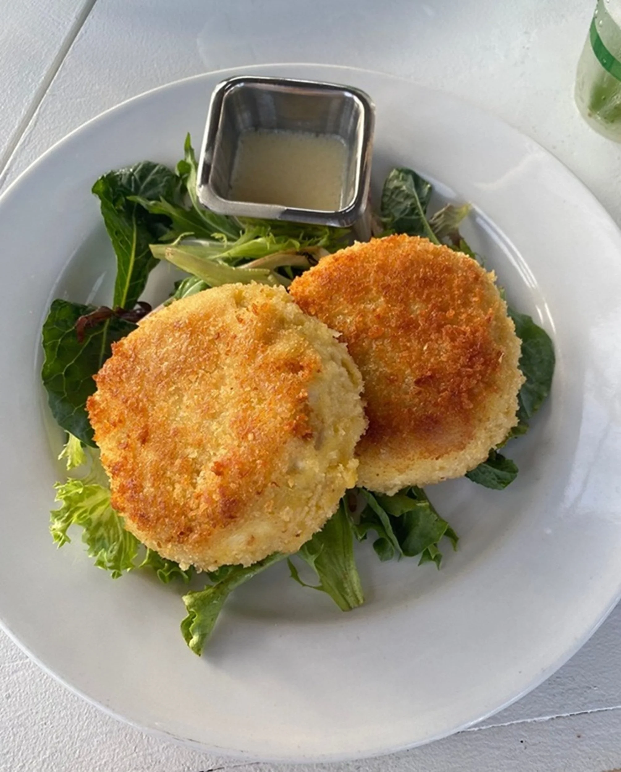 Golden Crab Cakes: Golden crab cakes served atop fresh greens celebrate the craftsmanship and coastal traditions of classic seafood cuisine. Rich texture, simple presentation, and authentic regional character make this image ideal for boutique hotels