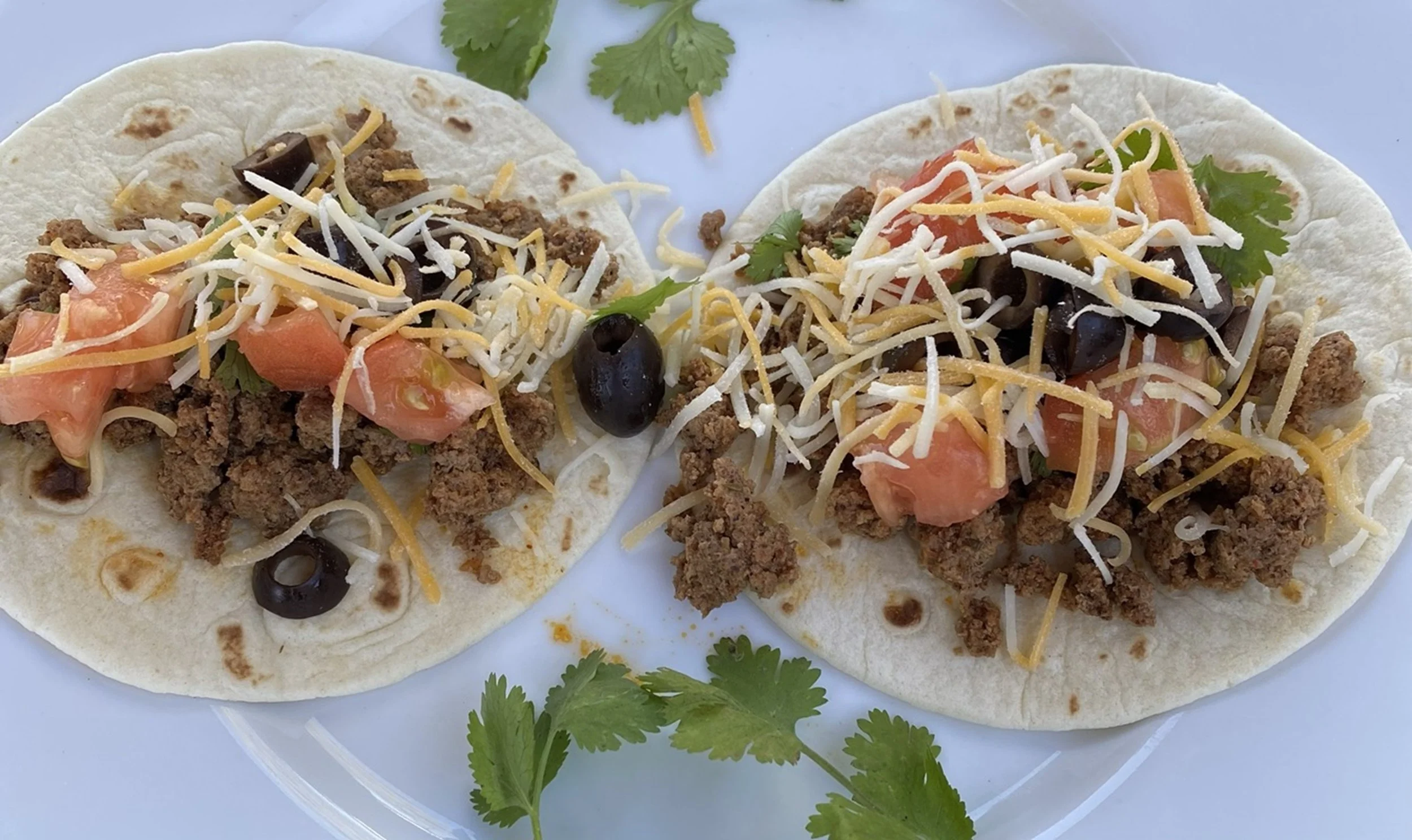 Street Table Tacos

Two soft tortillas layered with seasoned beef, fresh tomato, black olives, shredded cheese, and bright cilantro. Shot from above, the composition highlights color, texture, and the simplicity of a shared, casual meal.

Best Hospit
