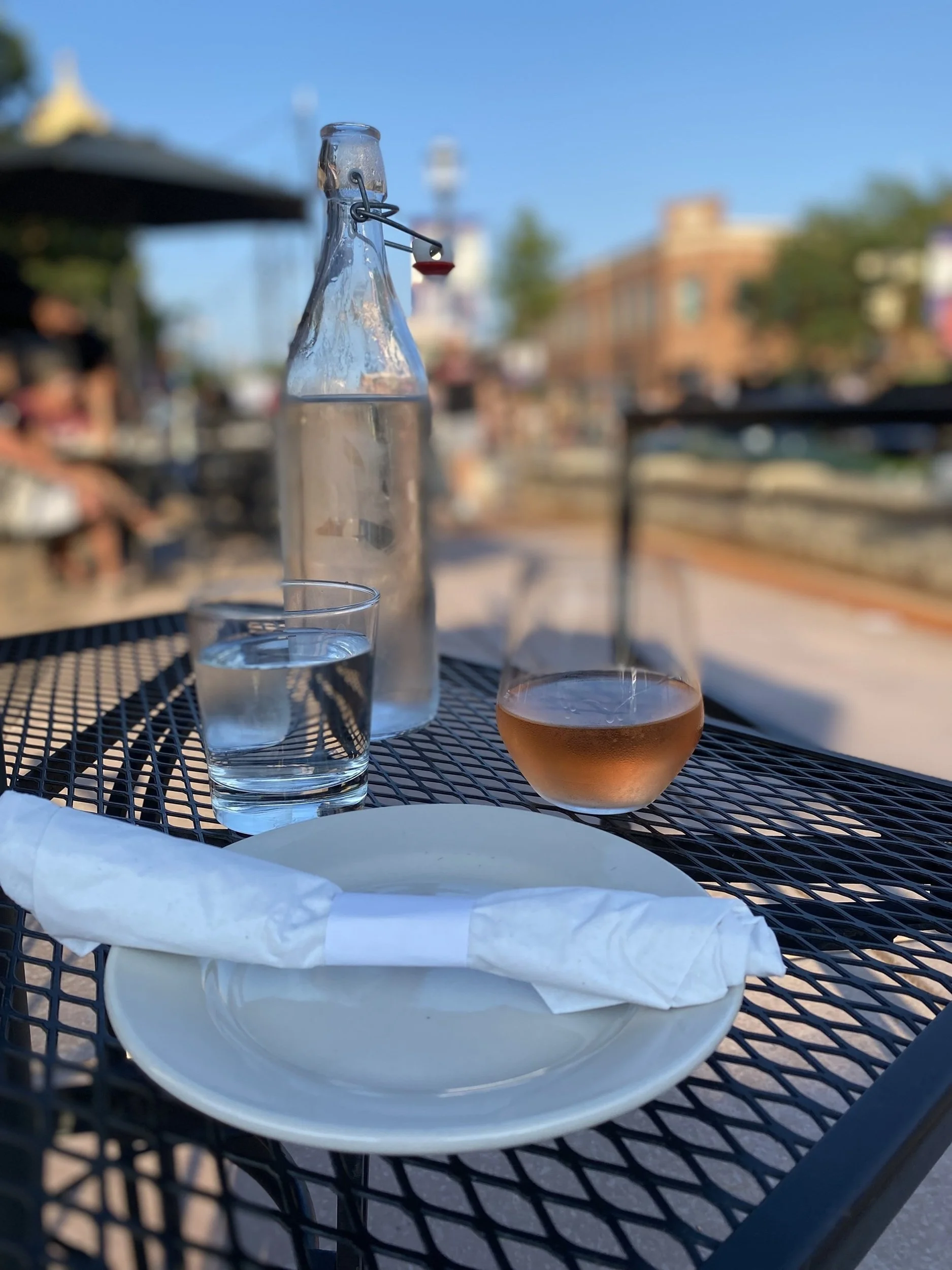 Before the First Course: A simple table setting with wine, water, and soft evening light captures the anticipation and quiet elegance that define memorable dining experiences. This image brings a sense of hospitality, relaxation, and refined simplici