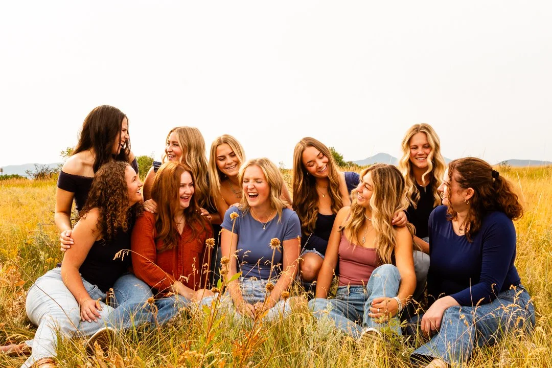 A group of ten professional sitting in a grassy field, laughing and enjoying each other's company on a sunny day. Warm branding and marketing organization photography in St. Augustine, Florida. Cinematic and personal.