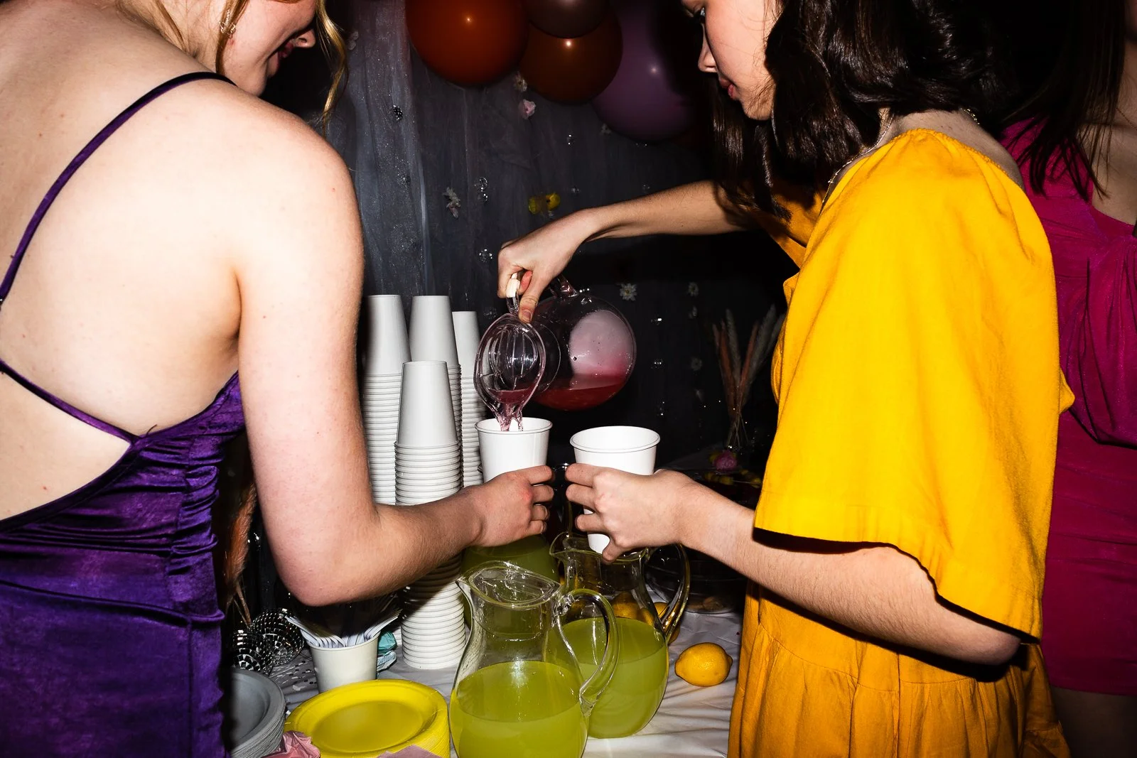 Candid party/event photo people pouring a pink punch into cups at a celebration. Cinematic film feeling, wedding and event photography in St. Augustine, FL. Fun, colorful and bright tones .
