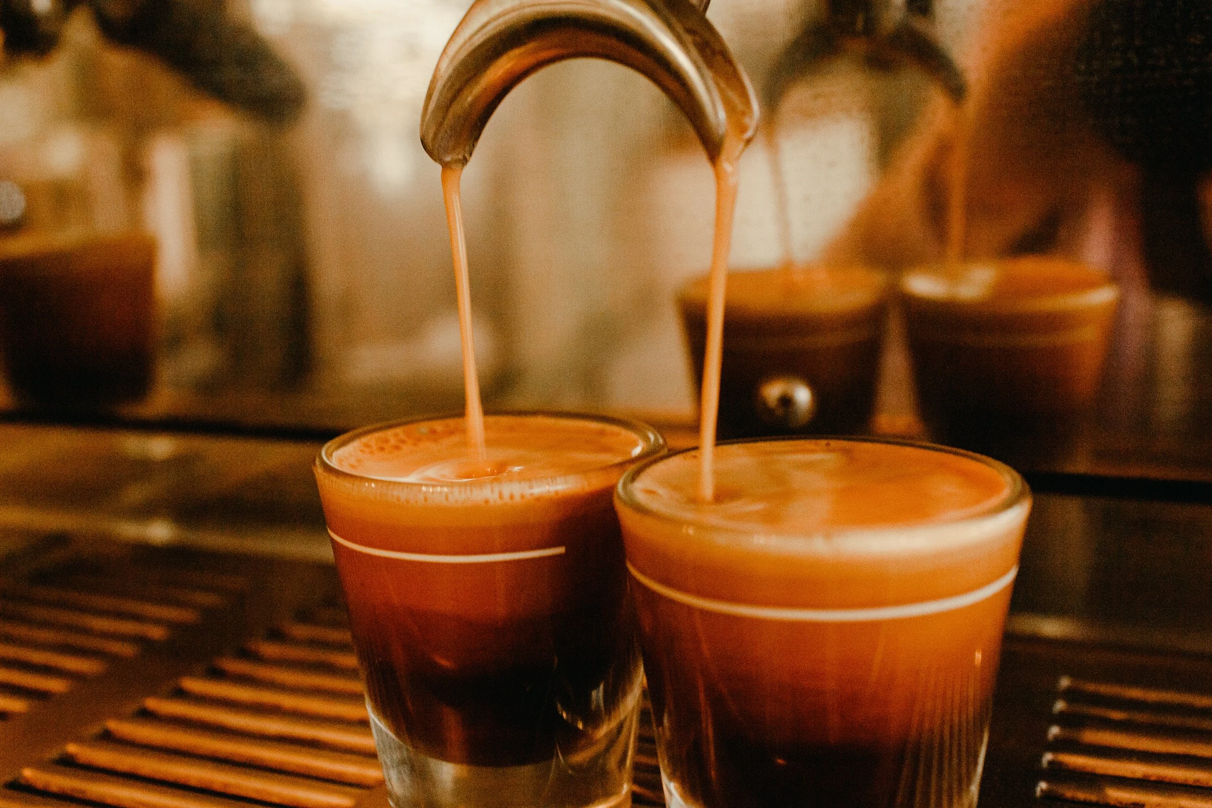 Warm detail photograph of espresso shots being pulled at a coffee shop. Restaurant social media content photography in St. Augustine, FL by Evelyn Elizabeth Photography.