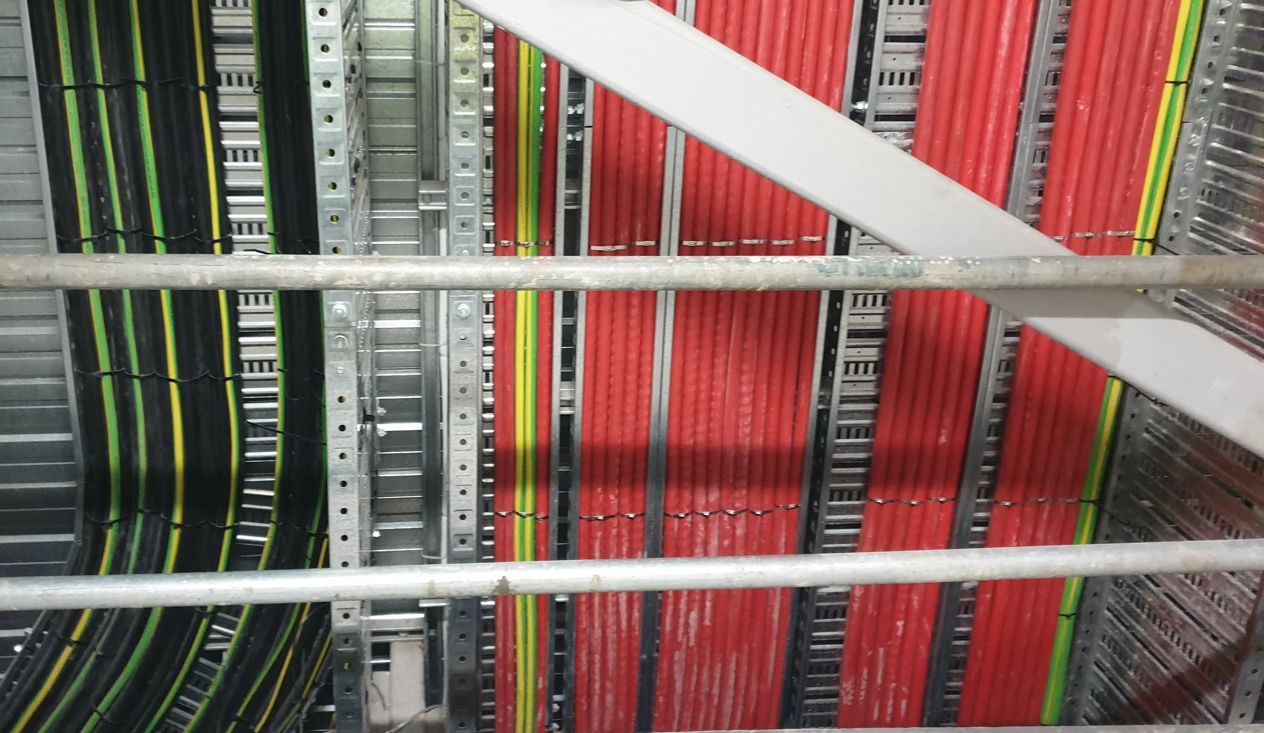 Close-up view of colorful organized electrical cables and wires on a metal cable management rack.