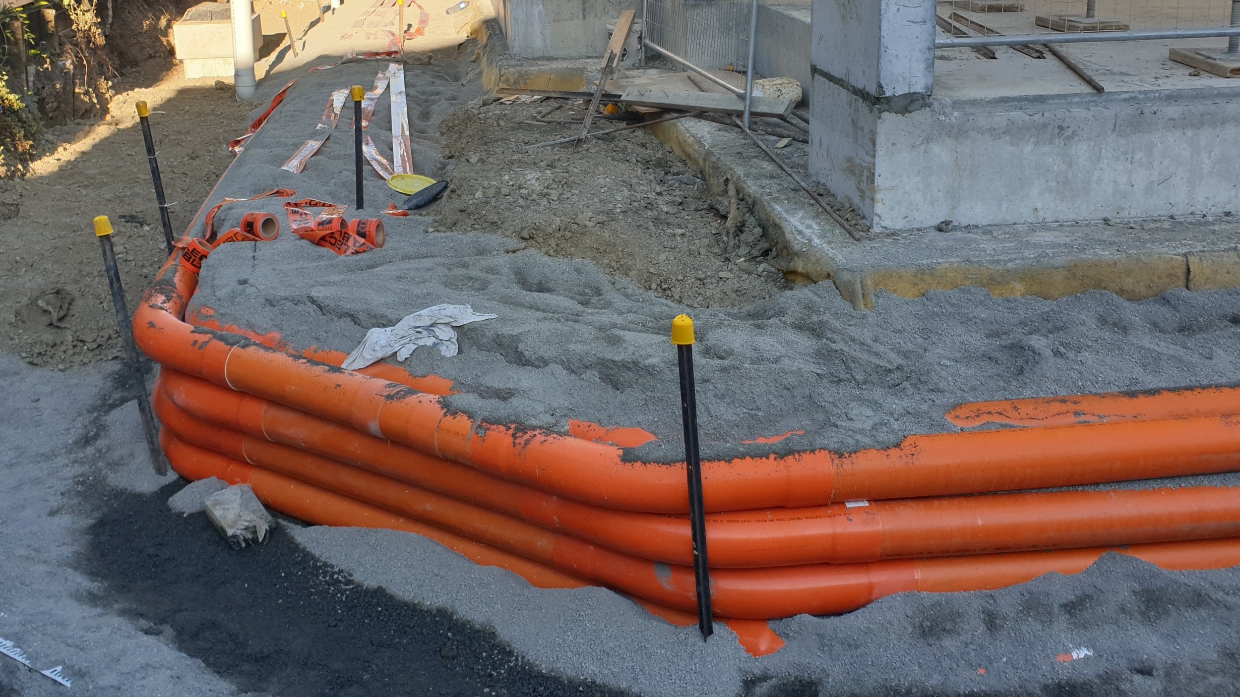 Construction site with orange pipes, dirt, and building materials.