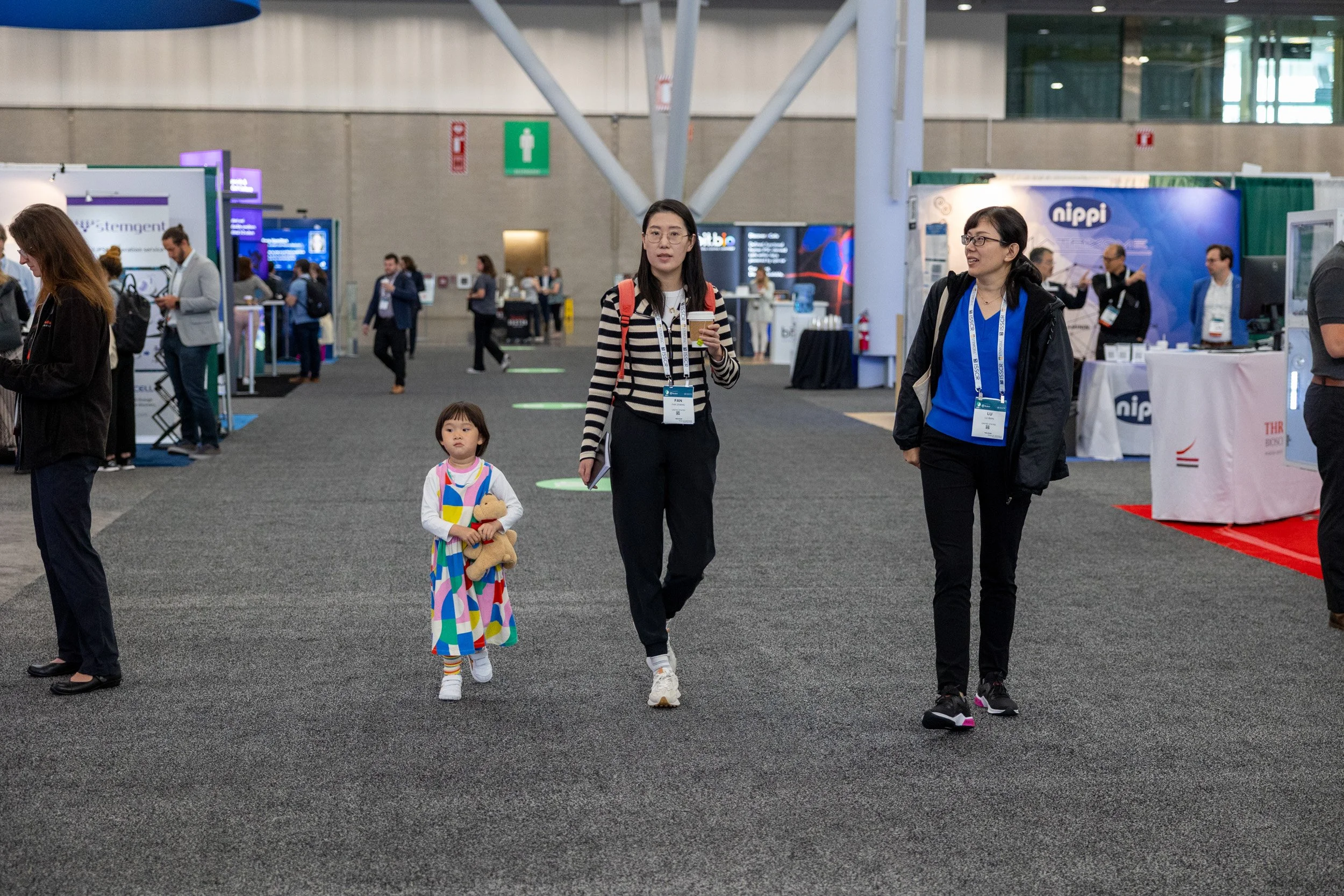 People walking in an exhibition hall with booths and displays.