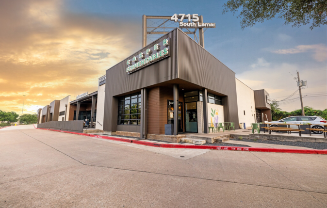Commercial building with a sign reading 'LASER REMOVABLES' at 4715 South Lamar, with an outdoor seating area and parked cars, under a partly cloudy sky.
