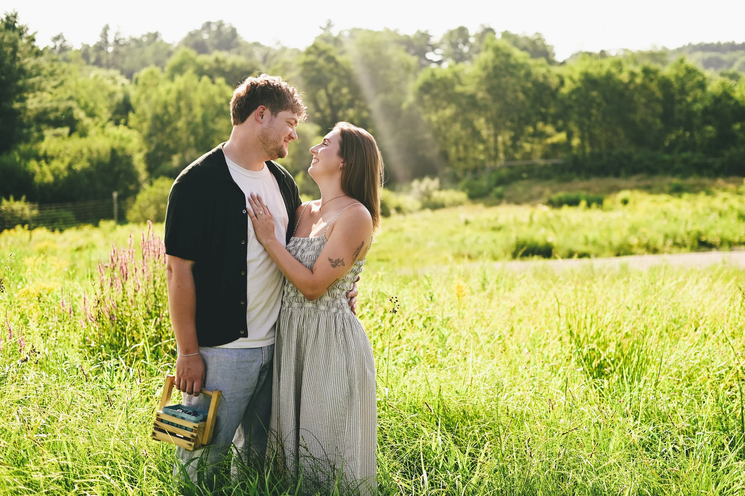 a couple smiling happily at each other in a field in Maine