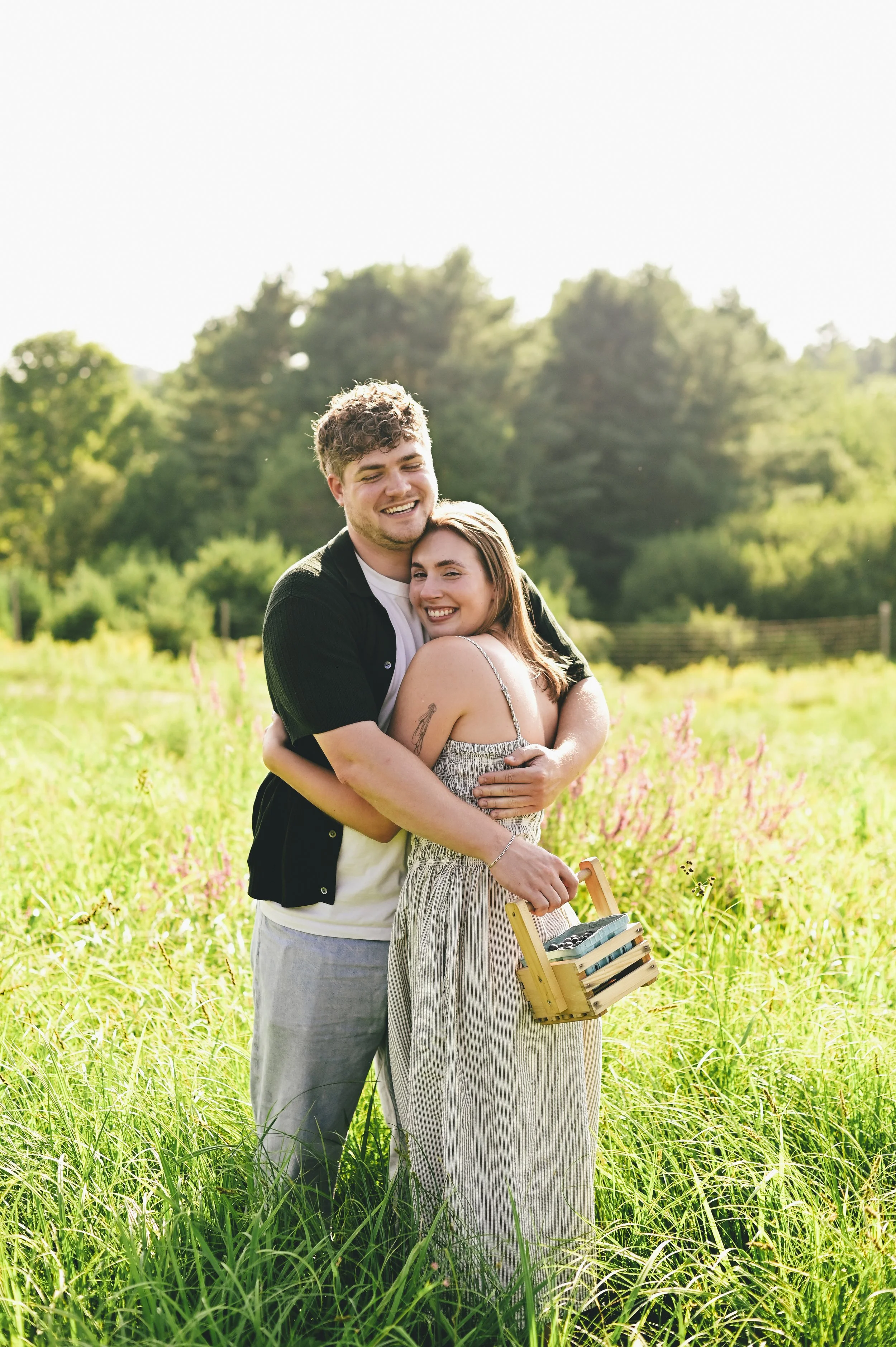 couple hugging in a field after picking blueberries