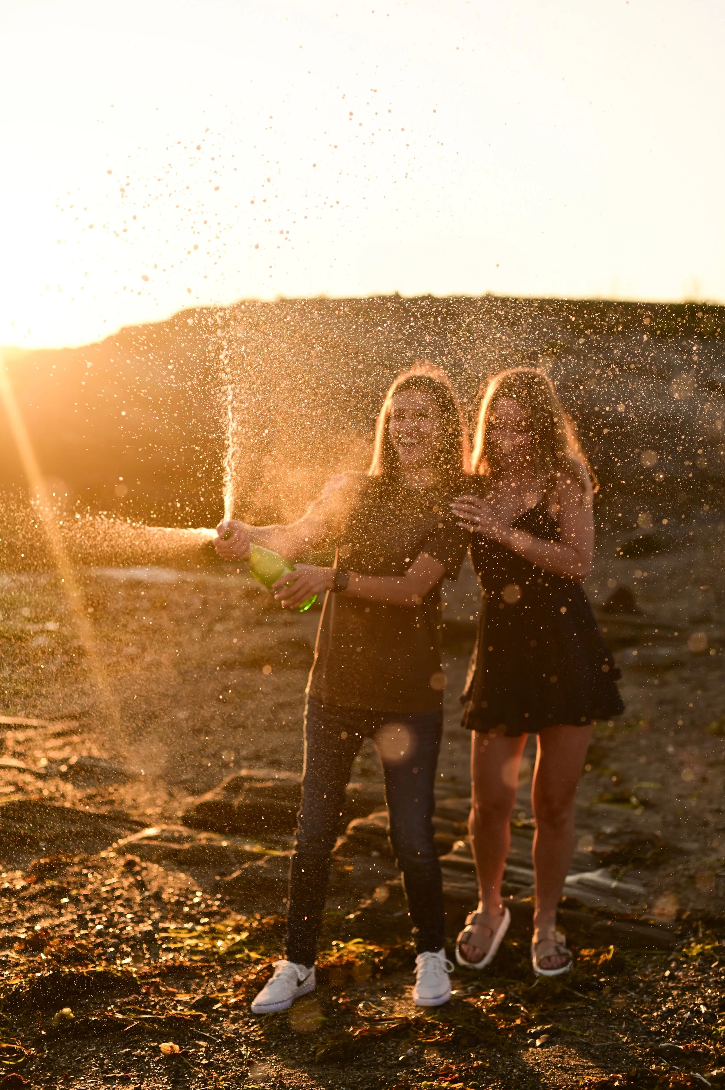 Future brides celebrating their engagement by popping champagne during golden hour