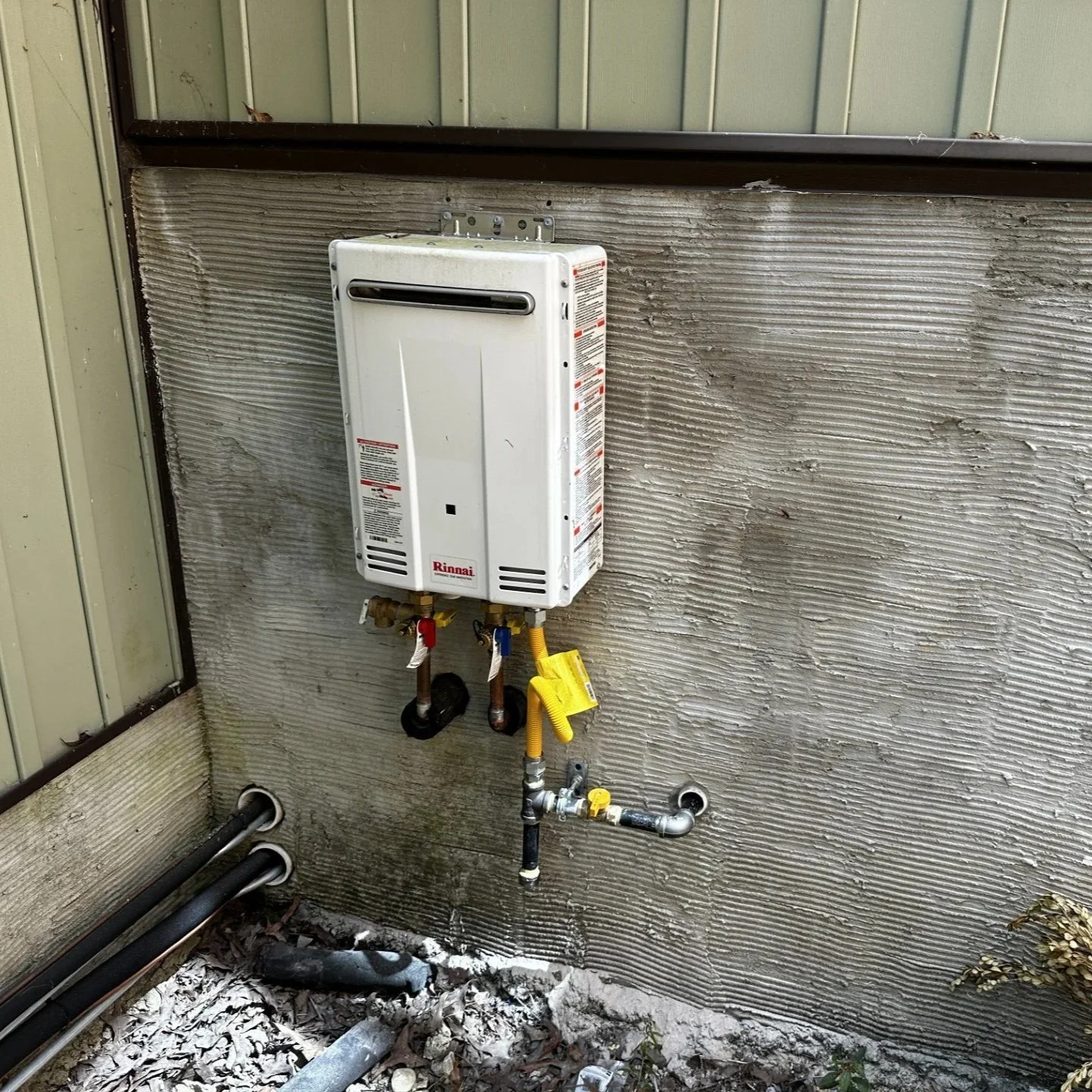 outdoor tankless water heater installed with water and gas connections.