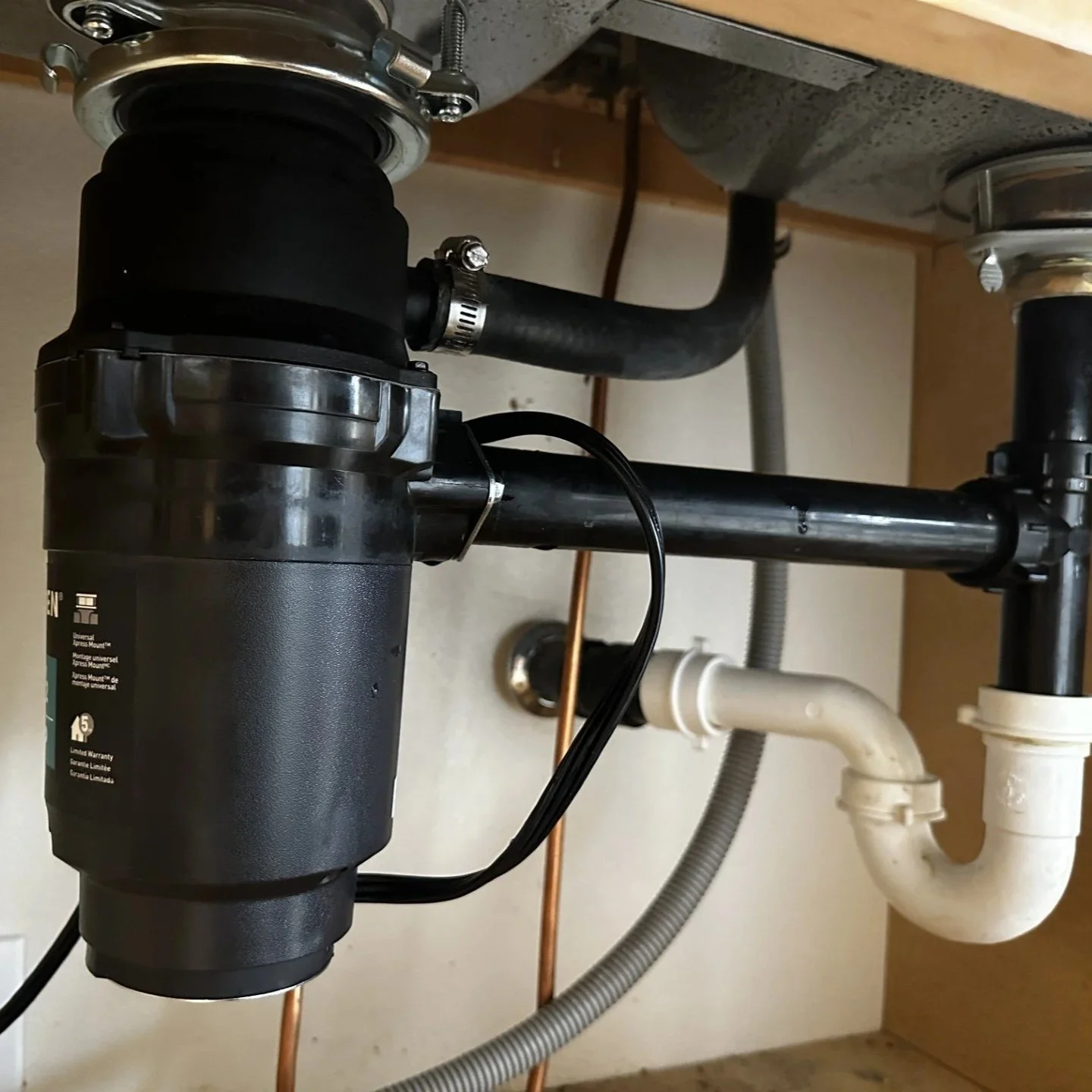 newly installed garbage disposal and under-sink drain plumbing.