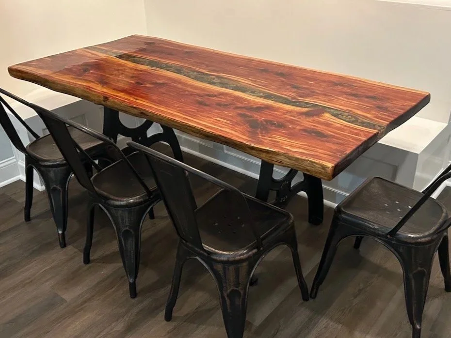 A custom live-edge wooden dining table with black metal legs.