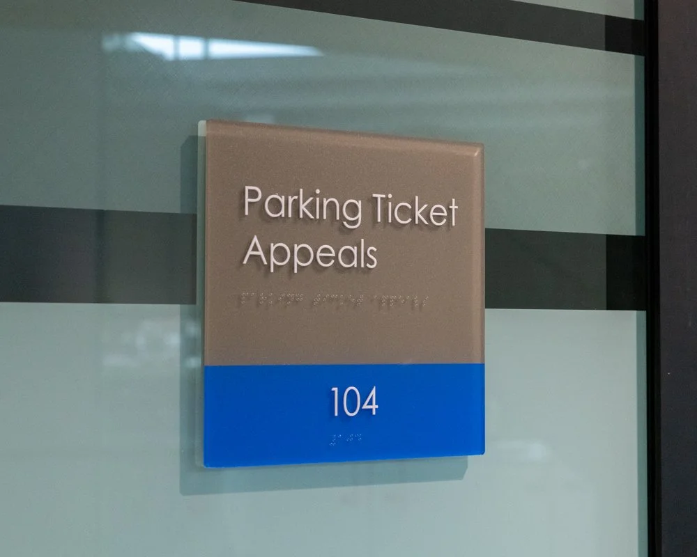 An office sign that reads the room number "104" and "Parking Ticket Appeals"