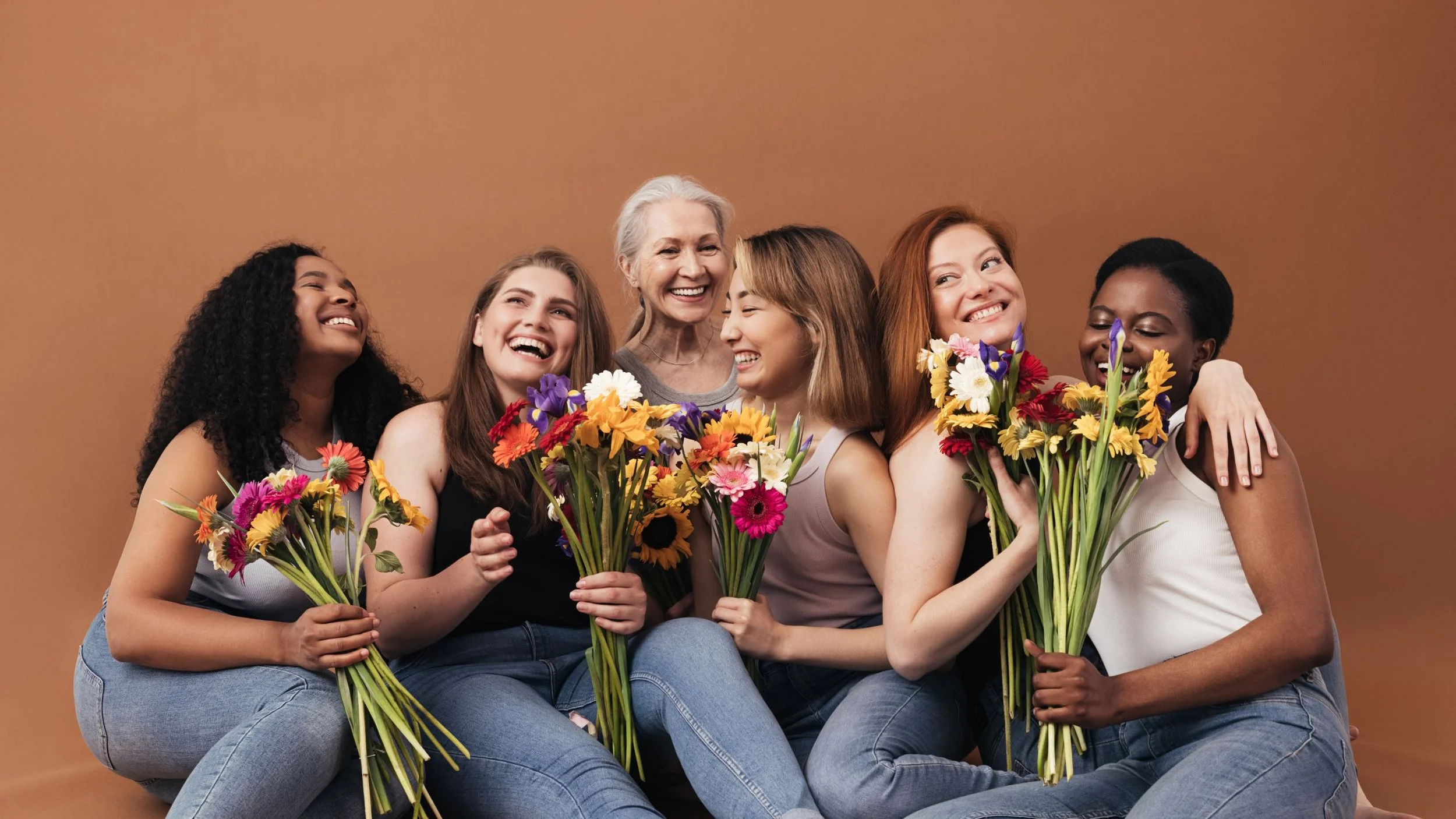A diverse group of women together on a brown background with flowers