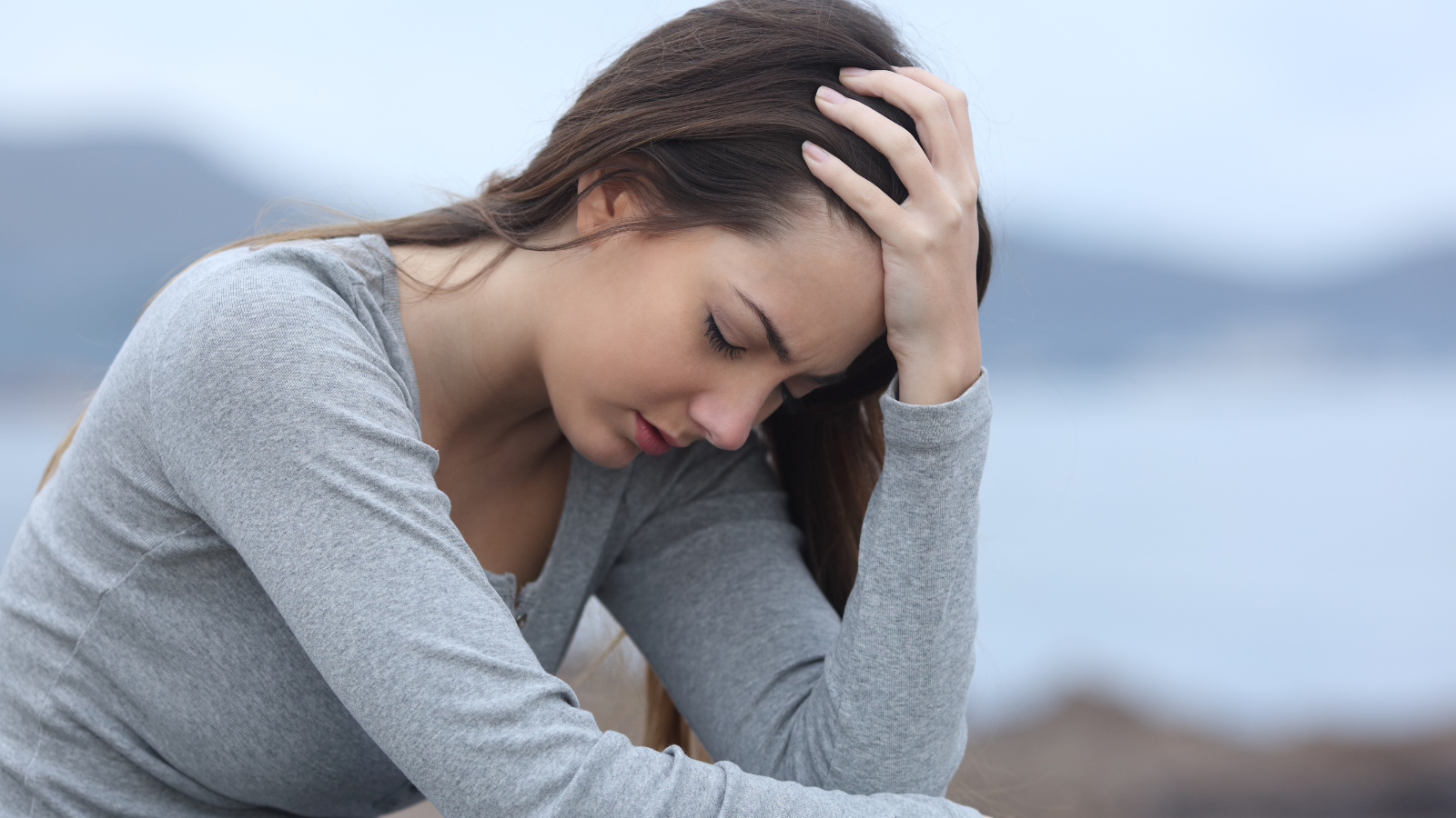 A woman who us stress with her hands to her hair