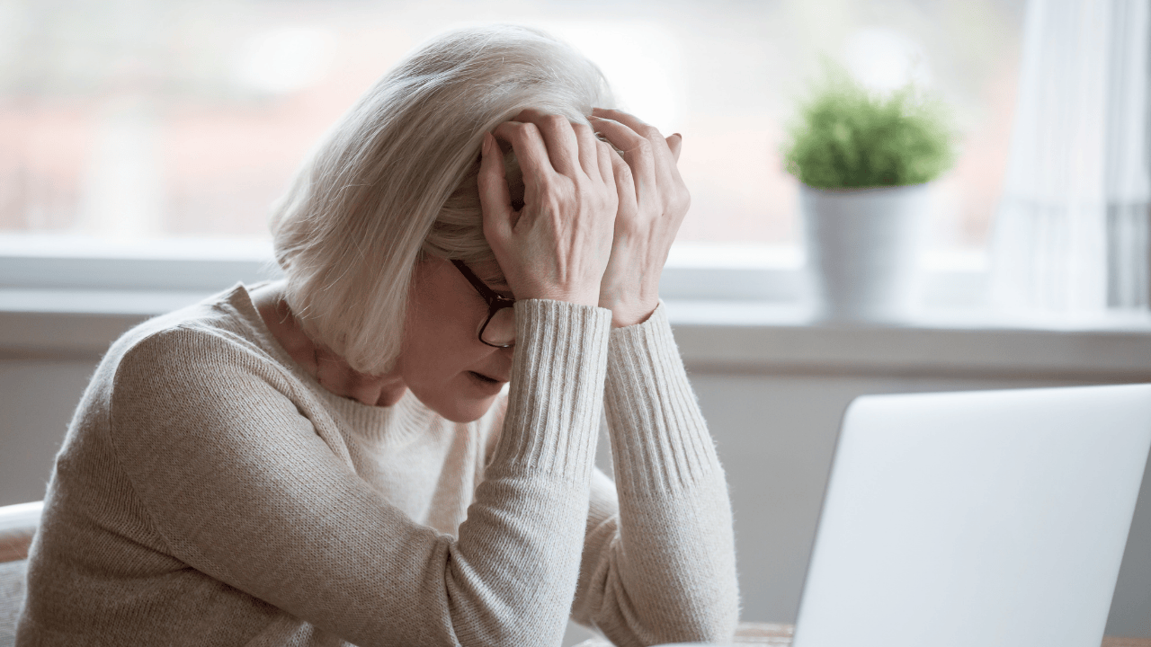 A middle age women who is stressed looking at her a laptop