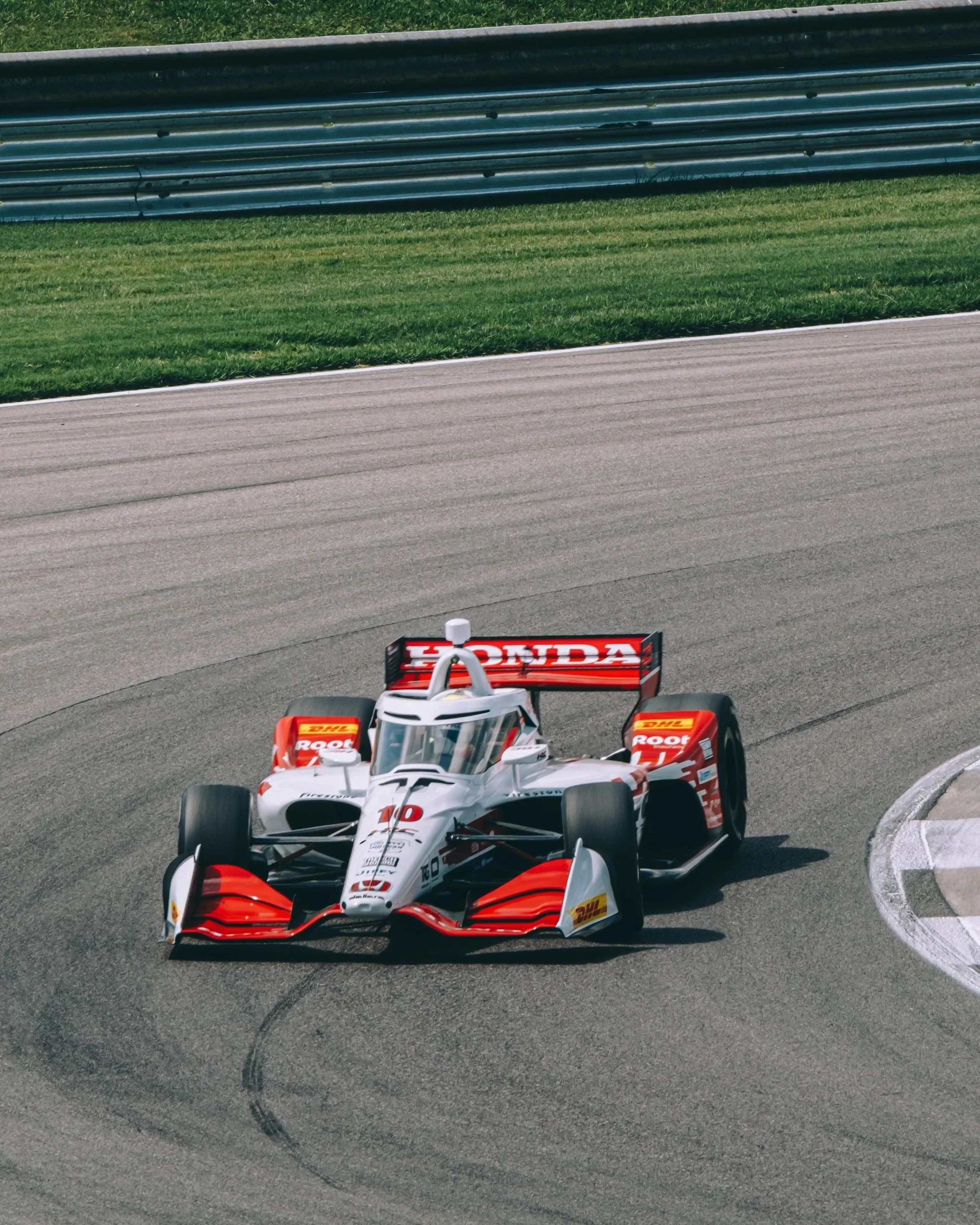 A red and white racing car with Honda branding on a race track.