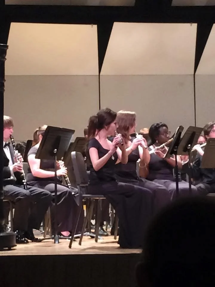Orchestra musicians playing wind instruments on stage during a concert