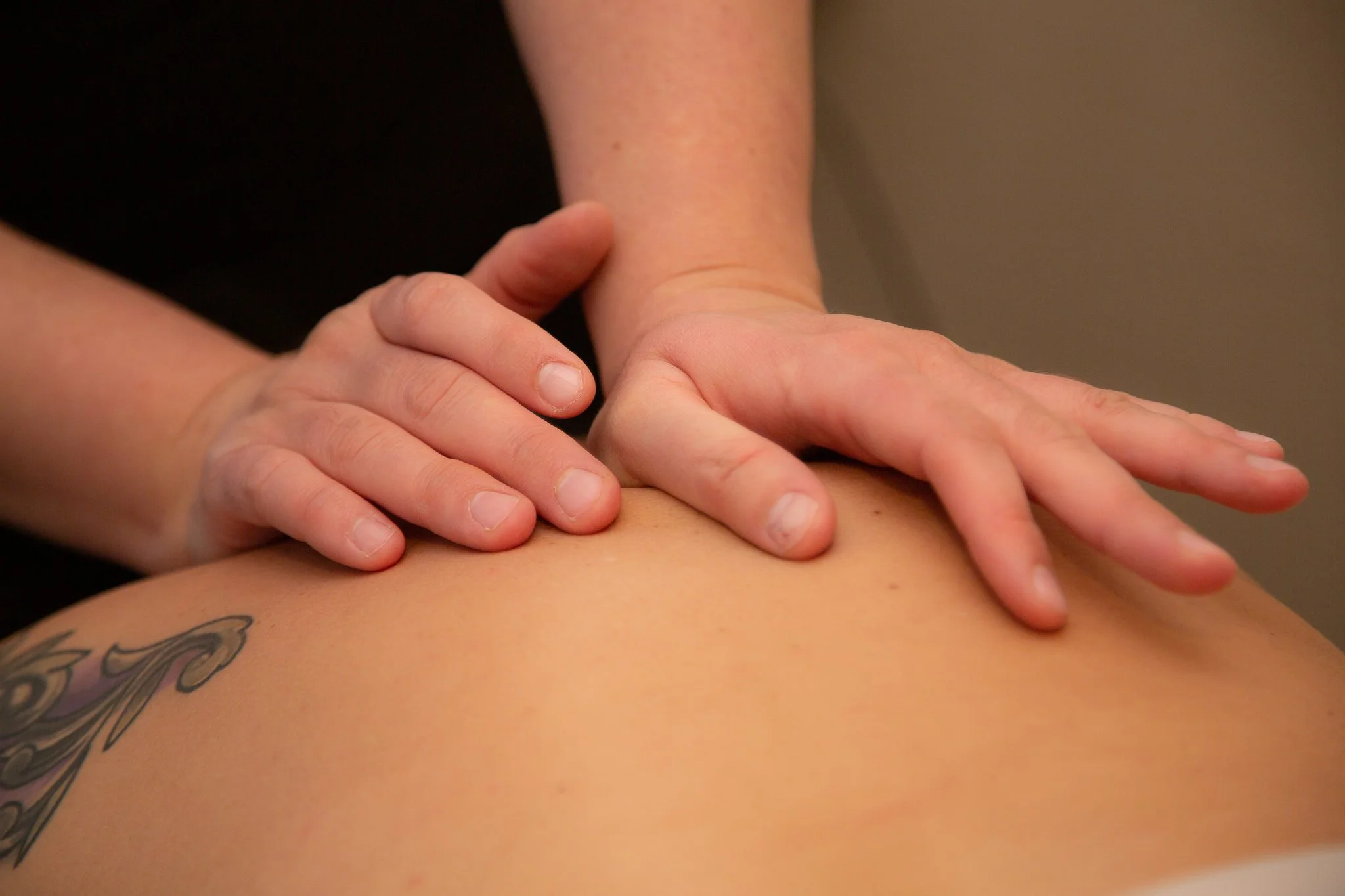 Close-up of a massage therapist's hands applying pressure on a person's back during a massage session.