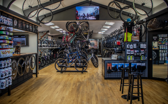 Bike shop interior with bikes on display, accessories, and a television mounted on the wall.