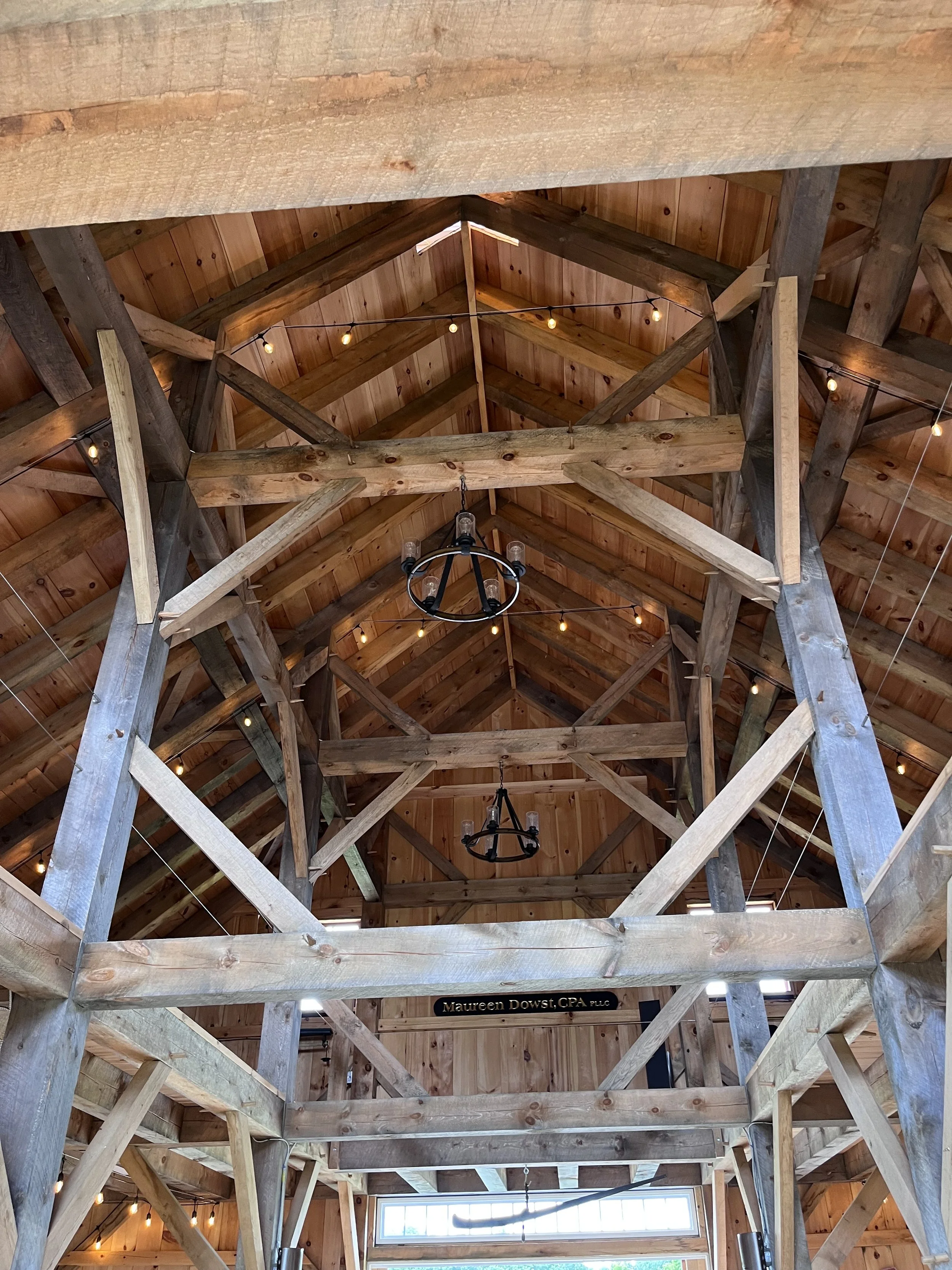 Interior view of a wooden building with exposed beams and string lights hanging from the ceiling.