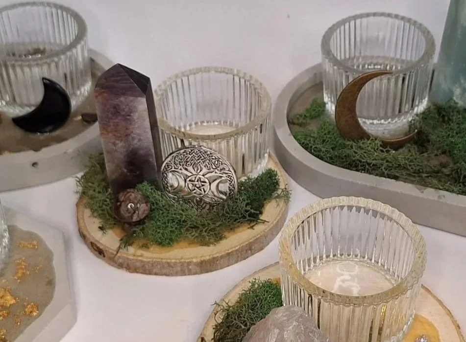 Decorative display of candles in glass holders, moon and star ornaments, and natural elements like moss and wood slices.