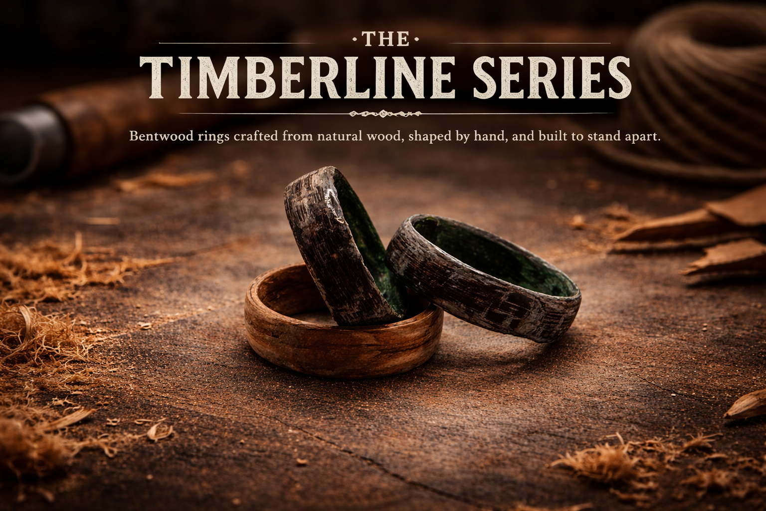 Two handcrafted bentwood rings made from natural wood, resting on a rustic wooden surface with woodworking tools in the background.