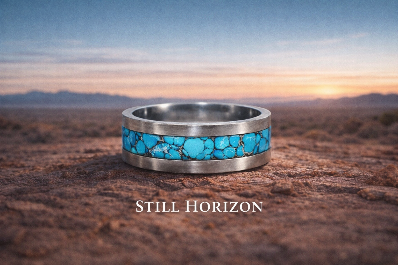 A silver ring with a turquoise stone inlay resting on a rocky surface during sunset with mountains in the background. The text 'Still Horizon' is overlaid at the bottom.