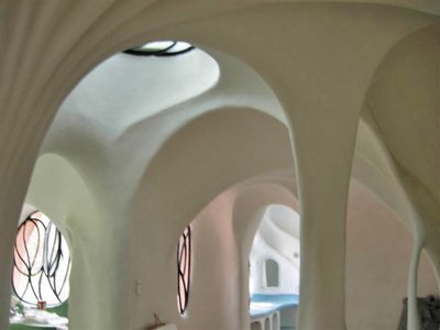 Interior view of a modern building with curvilinear white walls and ceiling, featuring oval and rounded windows.