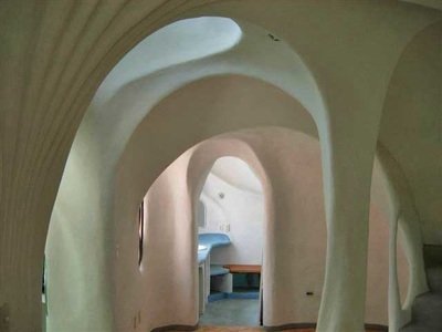 Interior view of a room with curved, organic architectural design and arched openings.