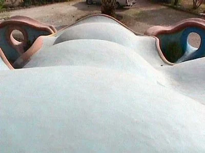 Close-up of a colorful playground slide shaped like a whale with curved sides and a rounded top.