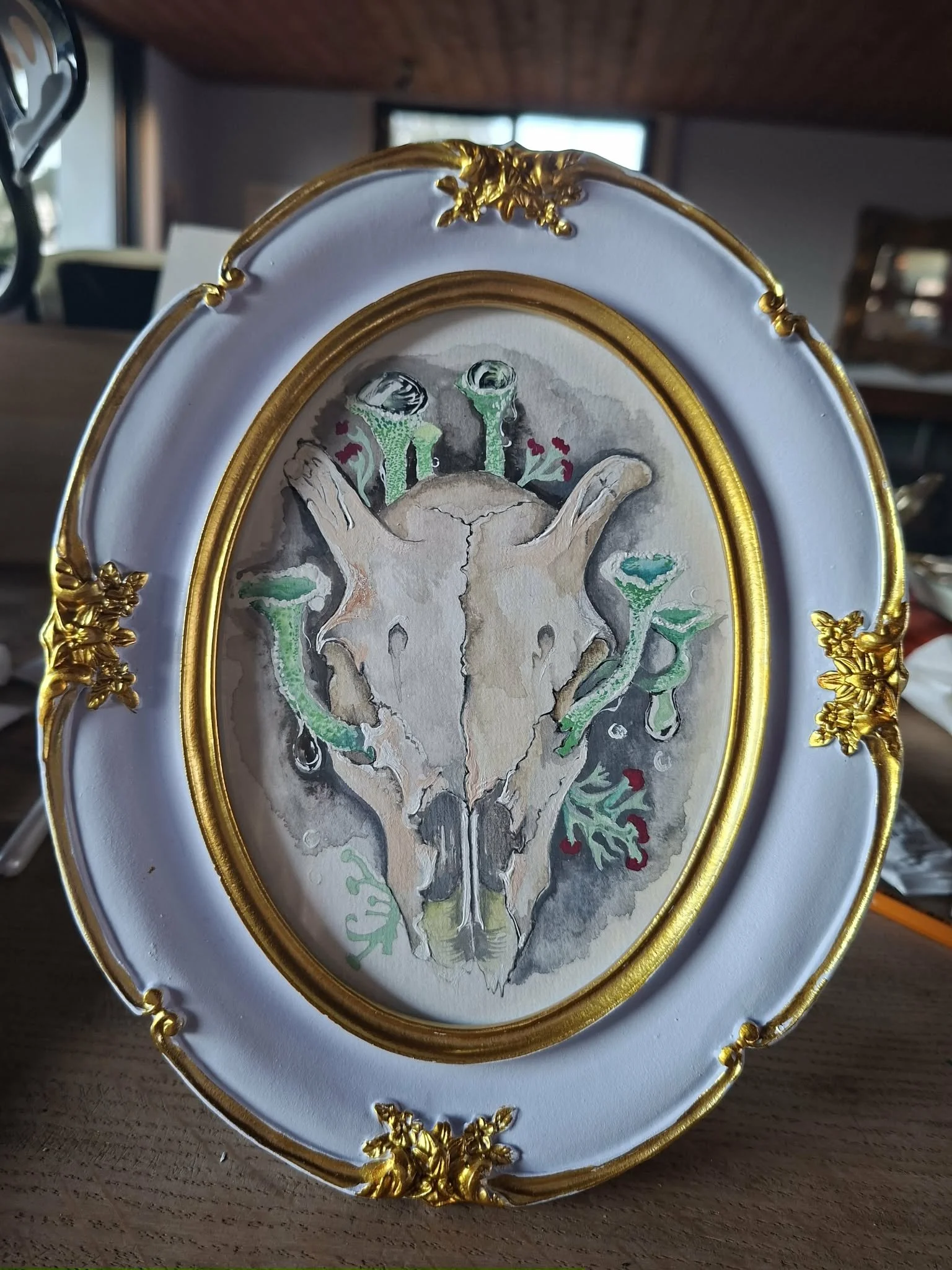 SOLD €150
“Larsma"

A study of a skull intertwined with emerging fungi, balancing decay and renewal. Soft washes of gouache and muted tones create a sense of age and stillness, while subtle green forms of trumpet Lichen suggest life continuing quietl