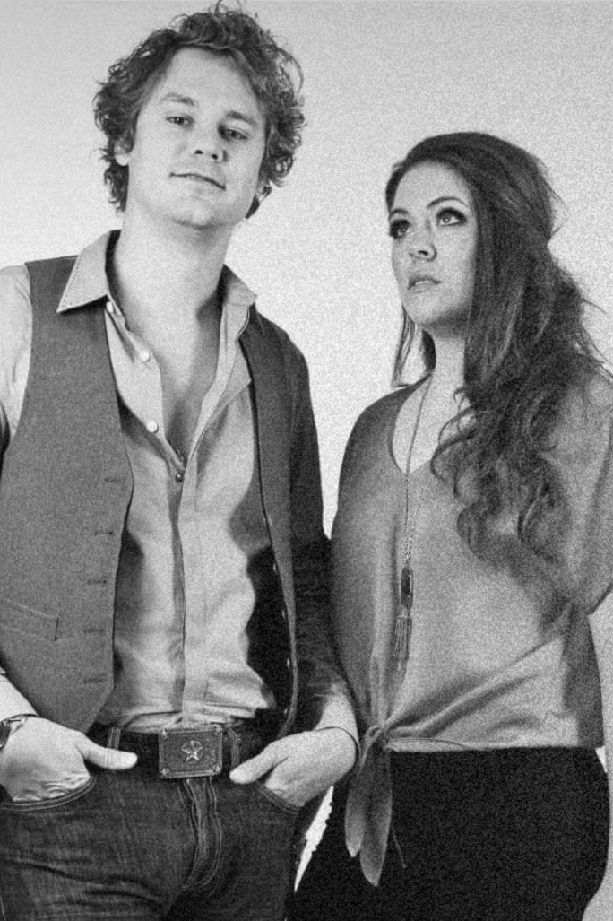 Black and white photo of a young man and woman standing side by side, dressed in casual and semi-formal clothing.