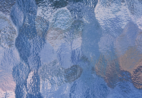 Abstract textured glass surface with a blue tint.