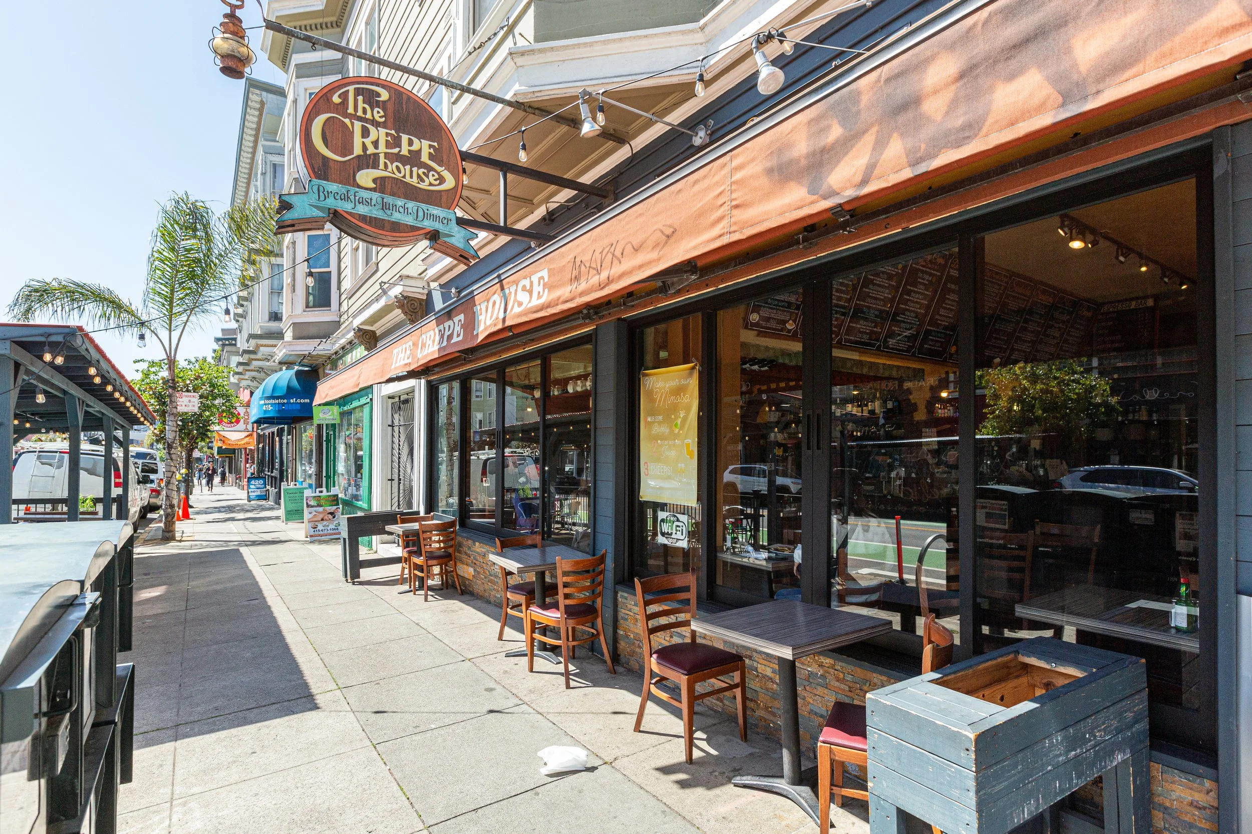 Exterior view of The Crepe House restaurant with outdoor seating, sidewalk, and signage on a bright day.