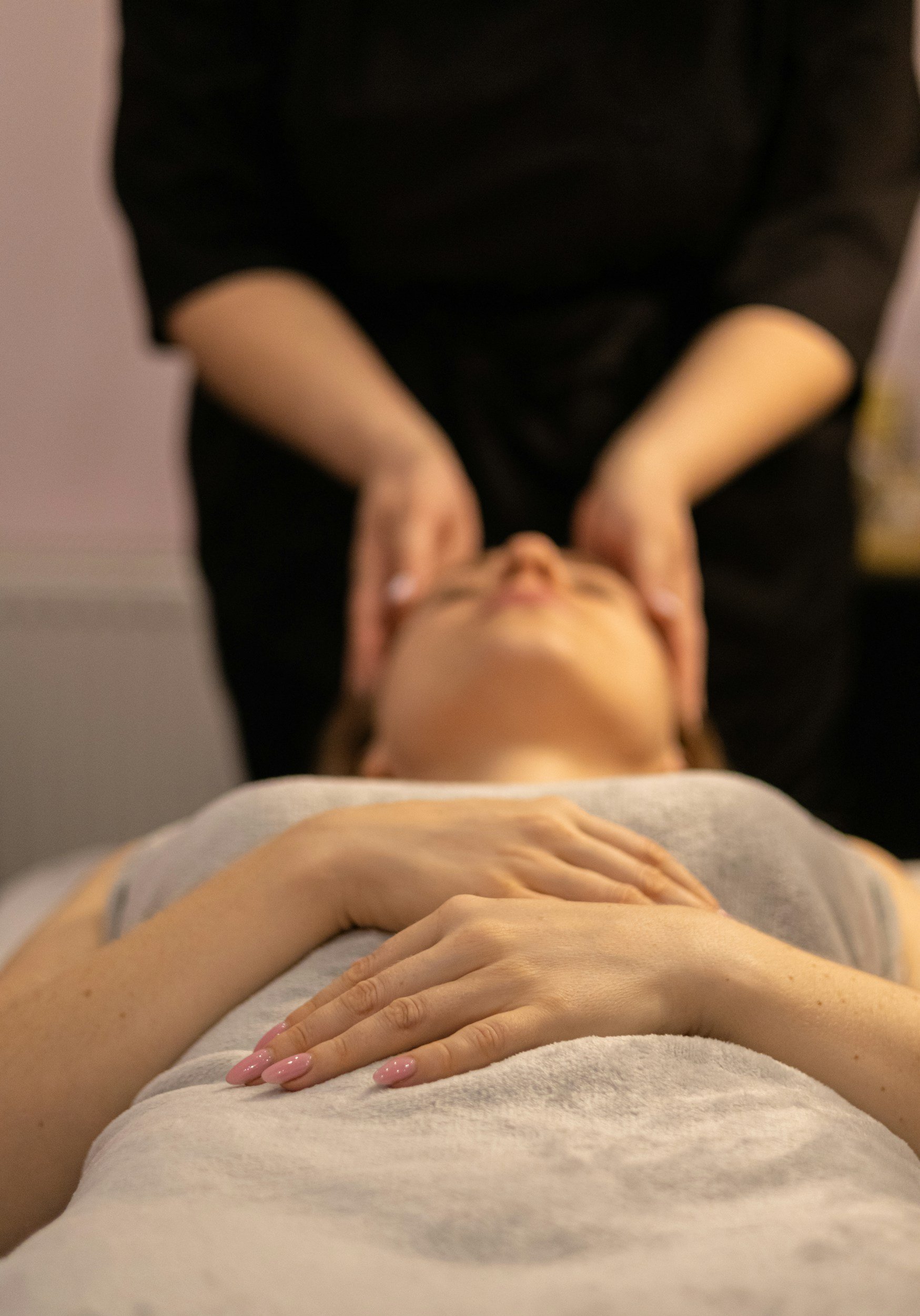 A person lying on a massage table with hands resting on their abdomen receiving a massage.
