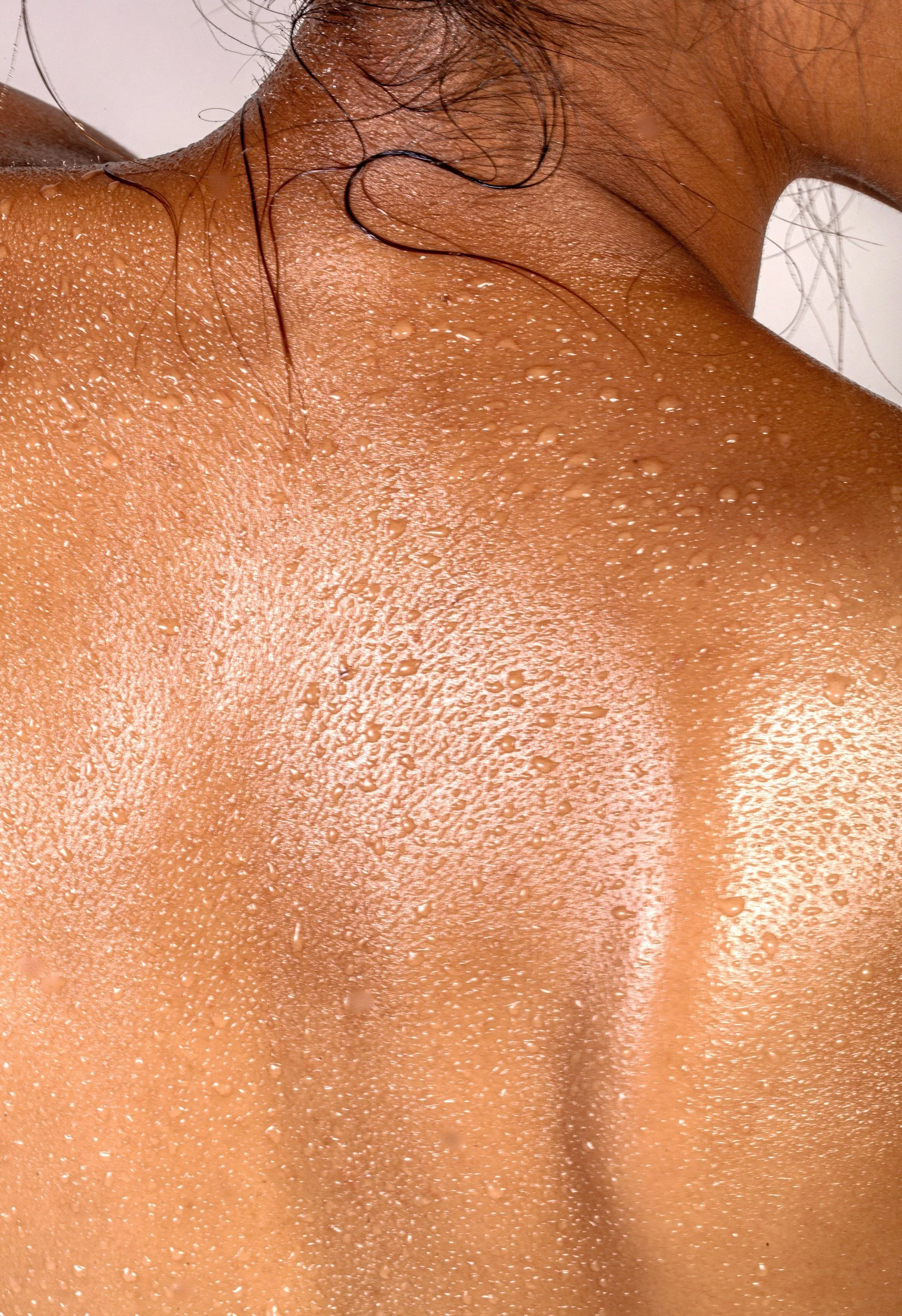 Close-up image of a person's neck and shoulder area with water droplets on the skin.