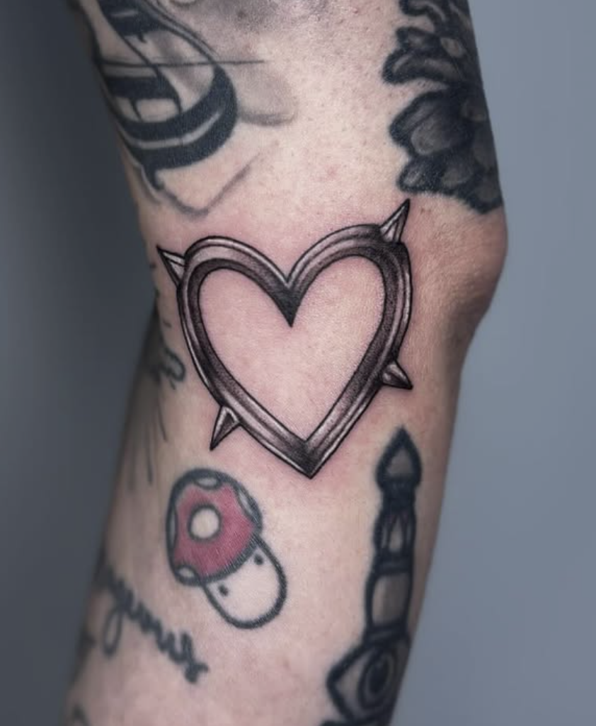 Tattoo of a heart with a spiked outline on a person's arm.