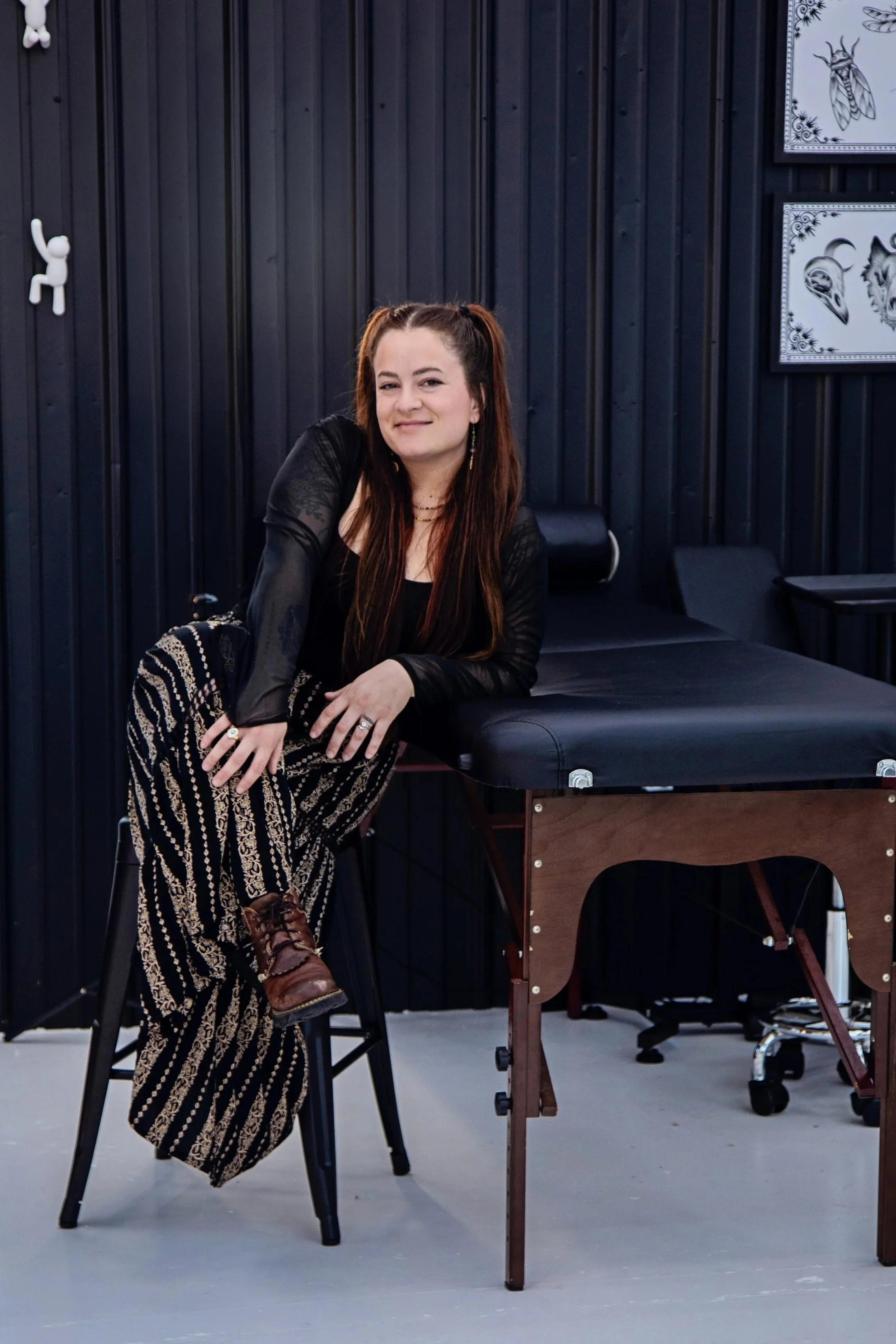 A black and white drawing of an owl with wings spread, surrounded by moon phases and a planet above its head.