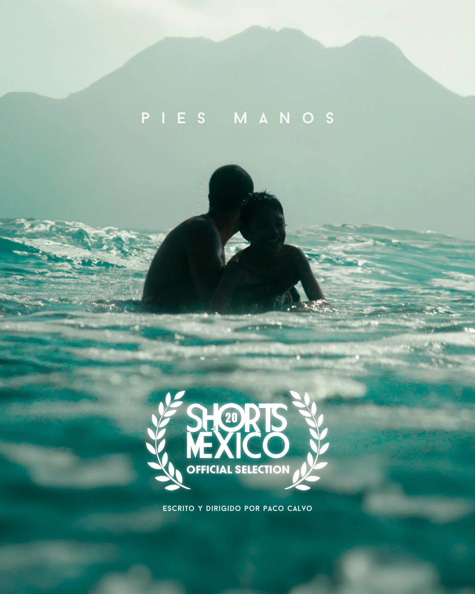 A picture of two children playing in the ocean with a mountain in the background, with the text 'PIES MANOS' at the top and 'SHORTS MEXICO OFFICIAL SELECTION' along with a laurel wreath symbol and the note 'ESCRITO Y DIRIGIDO POR PACO CALVO' at the bottom.