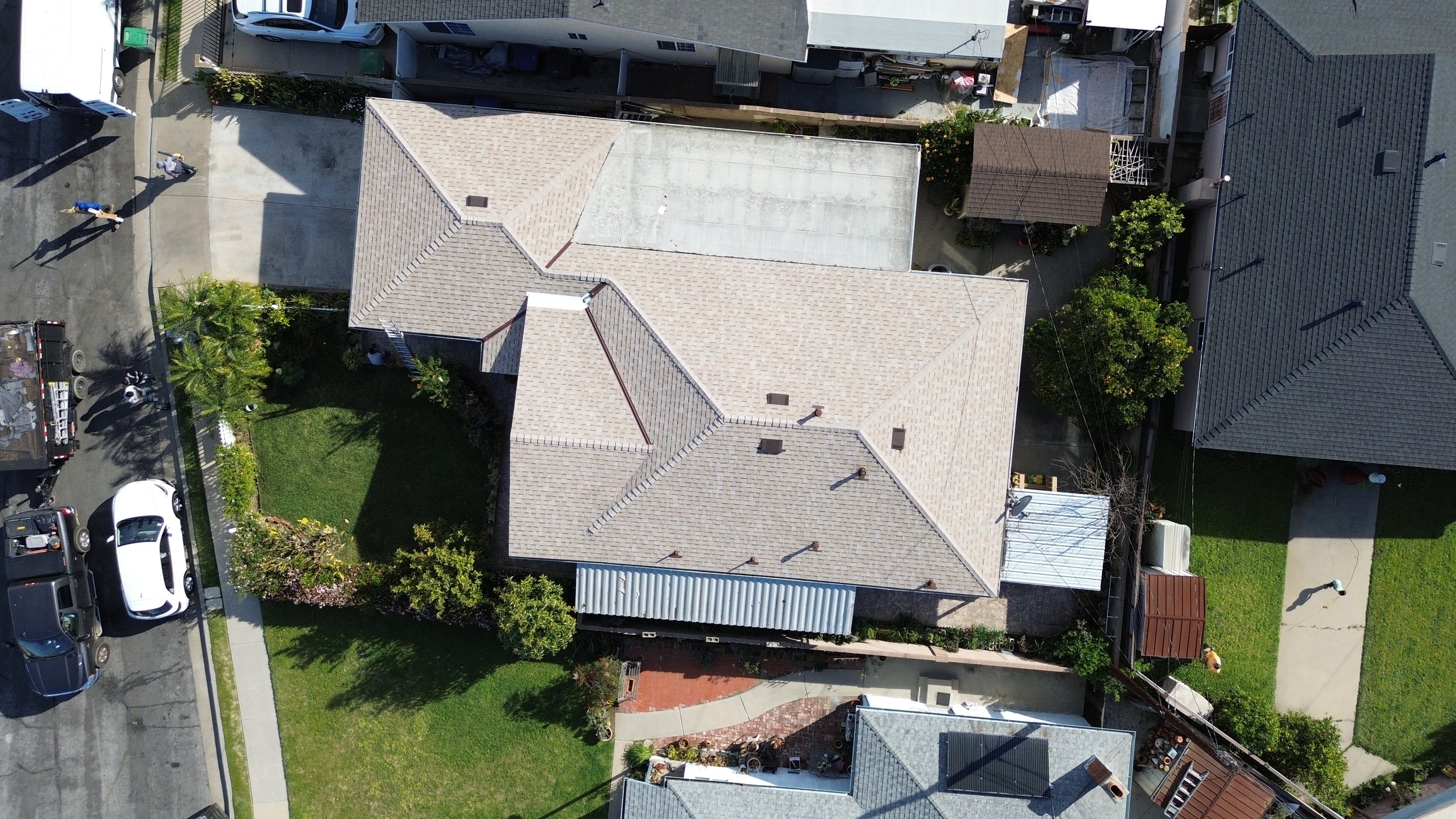 Aerial view of a residential neighborhood showing a house with a beige shingles roof.