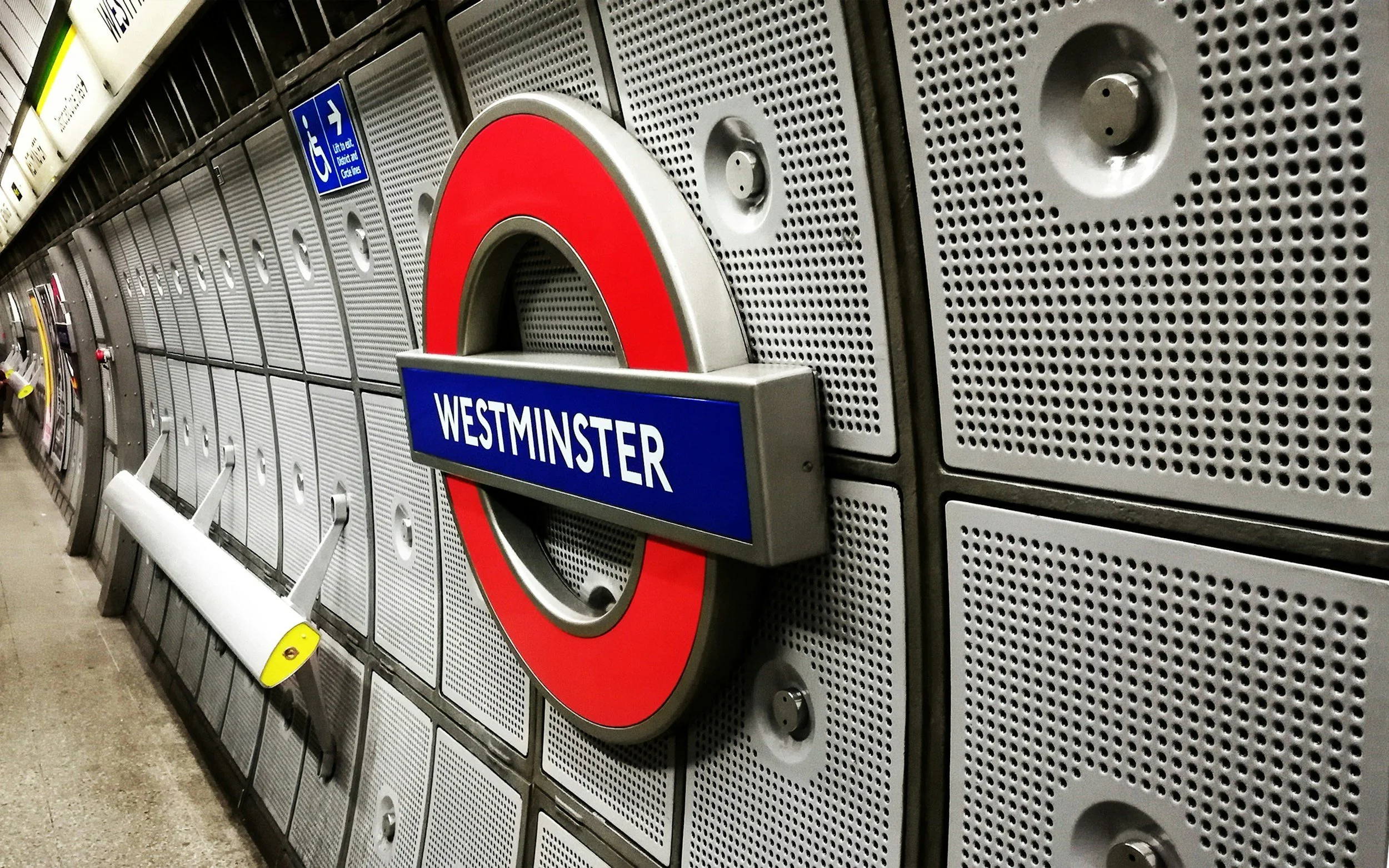 Sign displaying 'Westminster' in the London Underground station with lockers and a bench in the background.