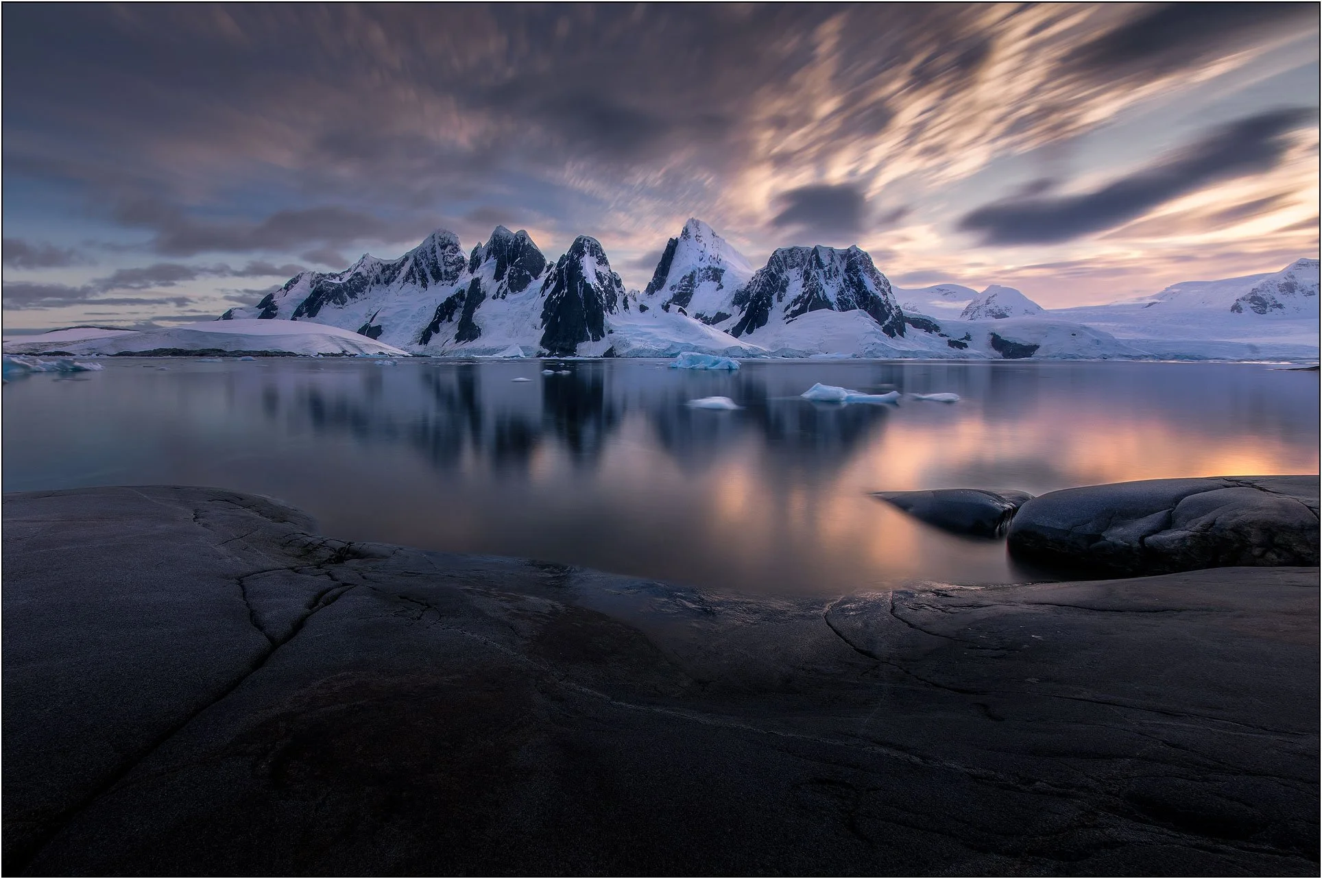 Slow shutter photograph of mountain and seascape during sunset in Antarctica peninsula.